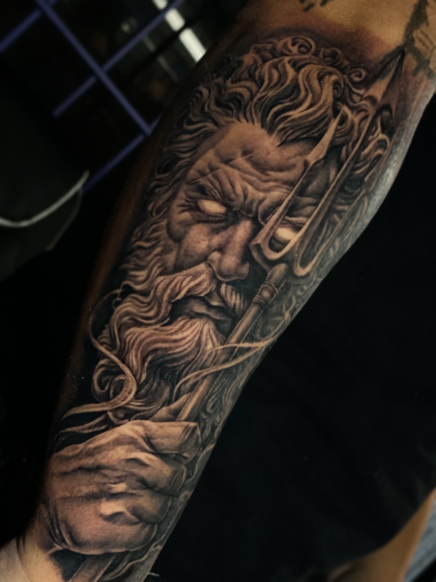 Bearded man with trident realism tattoo on the forearm by Seth Mullin, Hemet, California