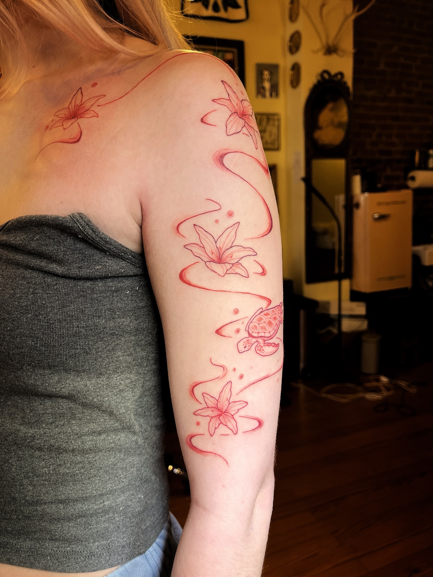 Lilies and turtles fine line tattoo on the upper arm by Risa Cincinnati Tattoo Artist