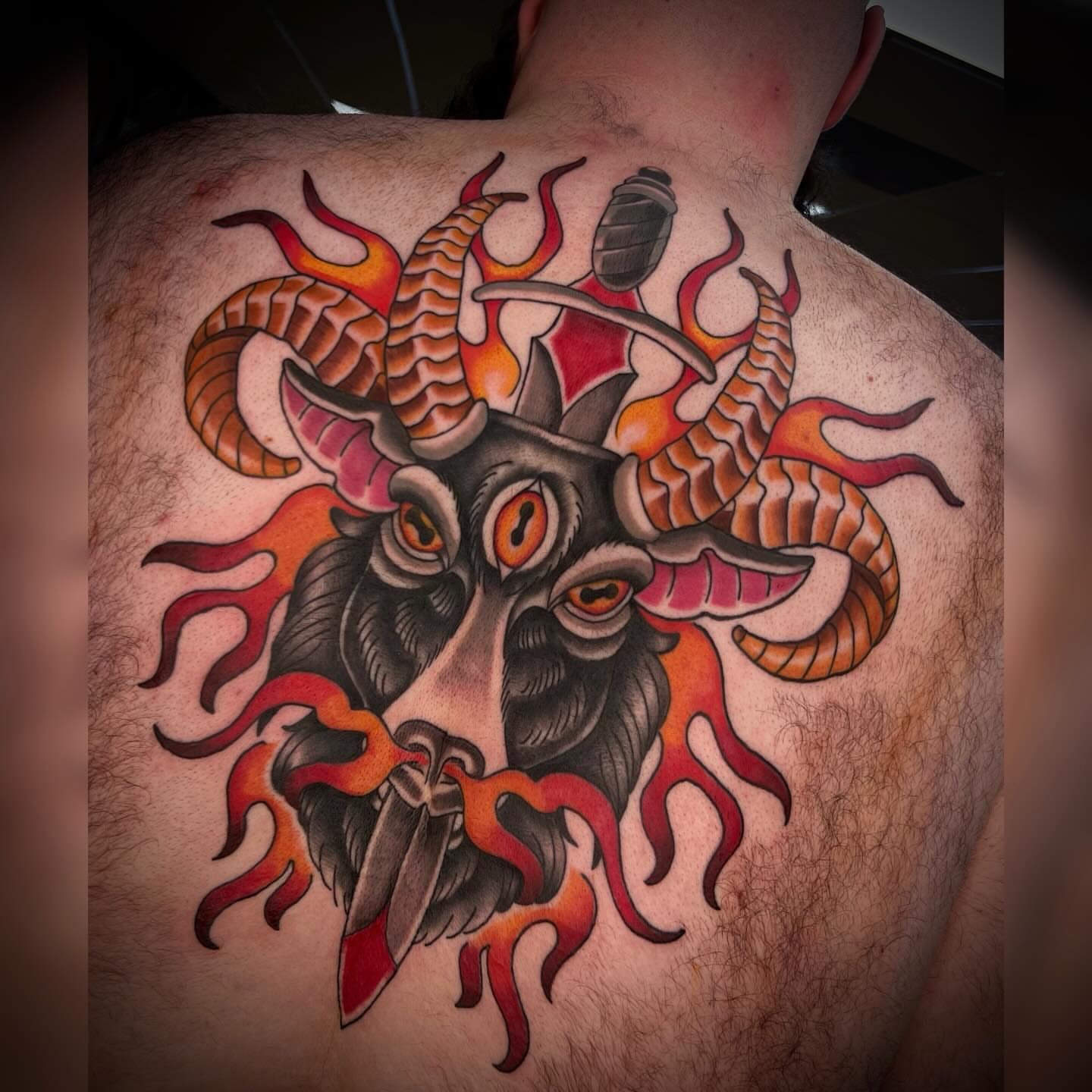 Goat head with flames American traditional tattoo on the back by Alyssa Deeghan