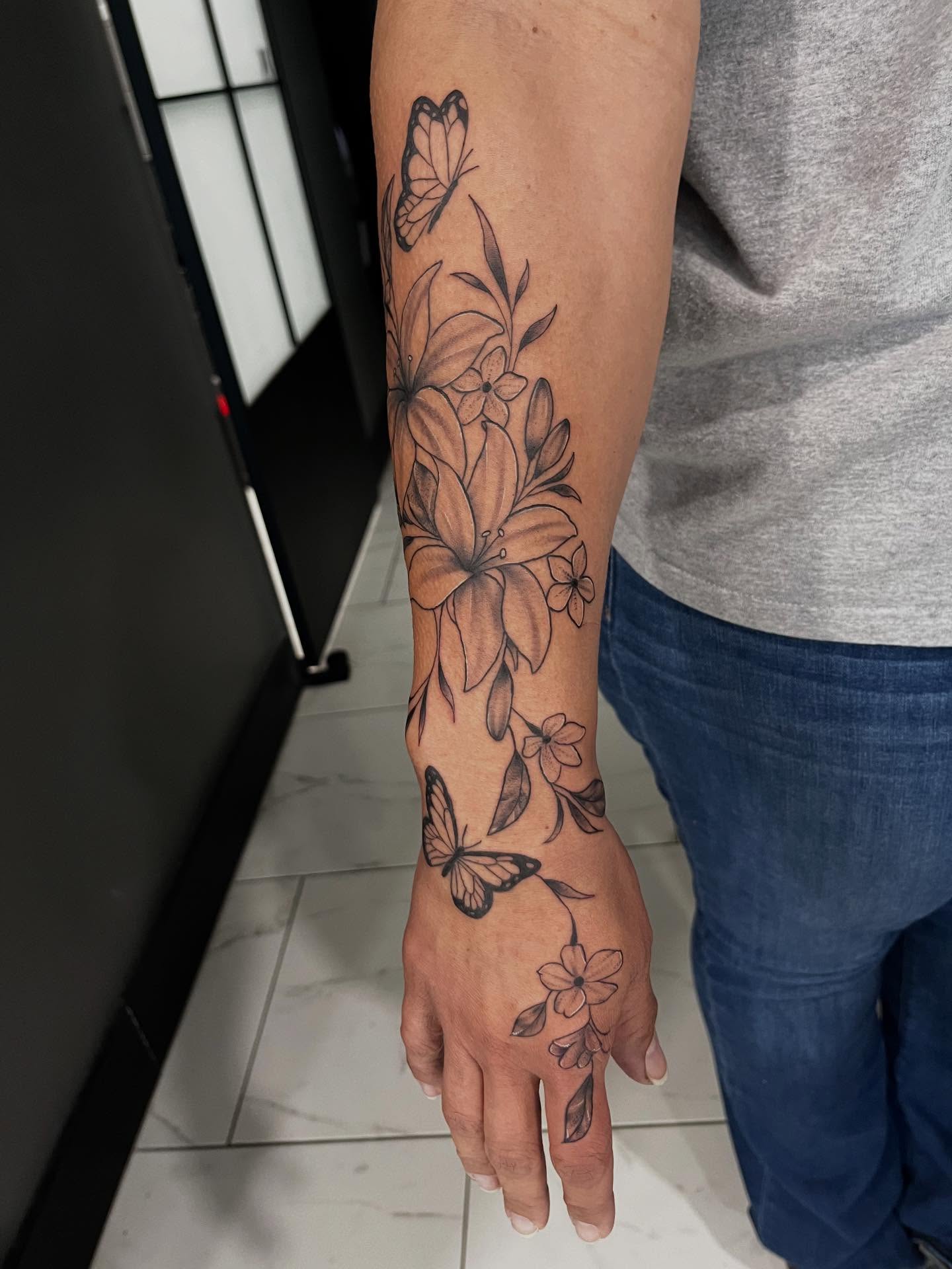 Flowers and butterflies black and grey tattoo on the forearm by Lexi Odam