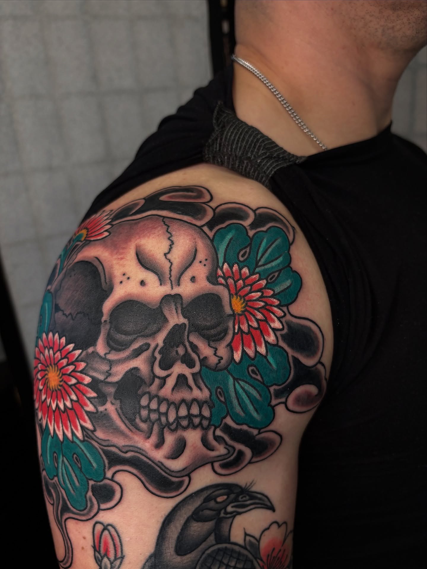 Skull and flowers American traditional tattoo on the shoulder by Dallas Tattoo Artist