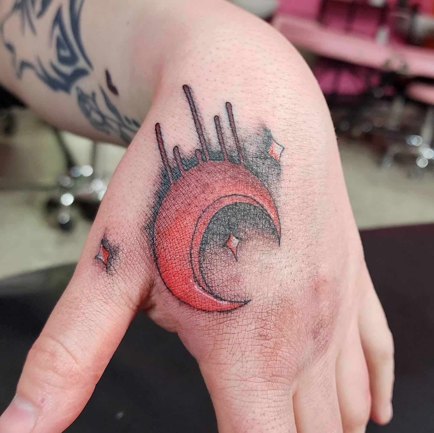 Red crescent moon dotwork tattoo on the hand by K.F. Golden