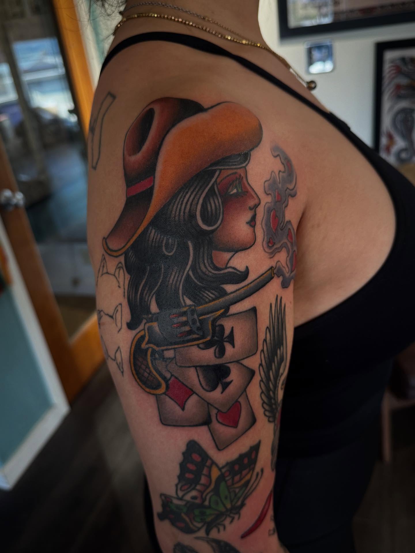 Cowgirl with gun American traditional tattoo on the upper arm by Laurent Trelaun, San Francisco, California