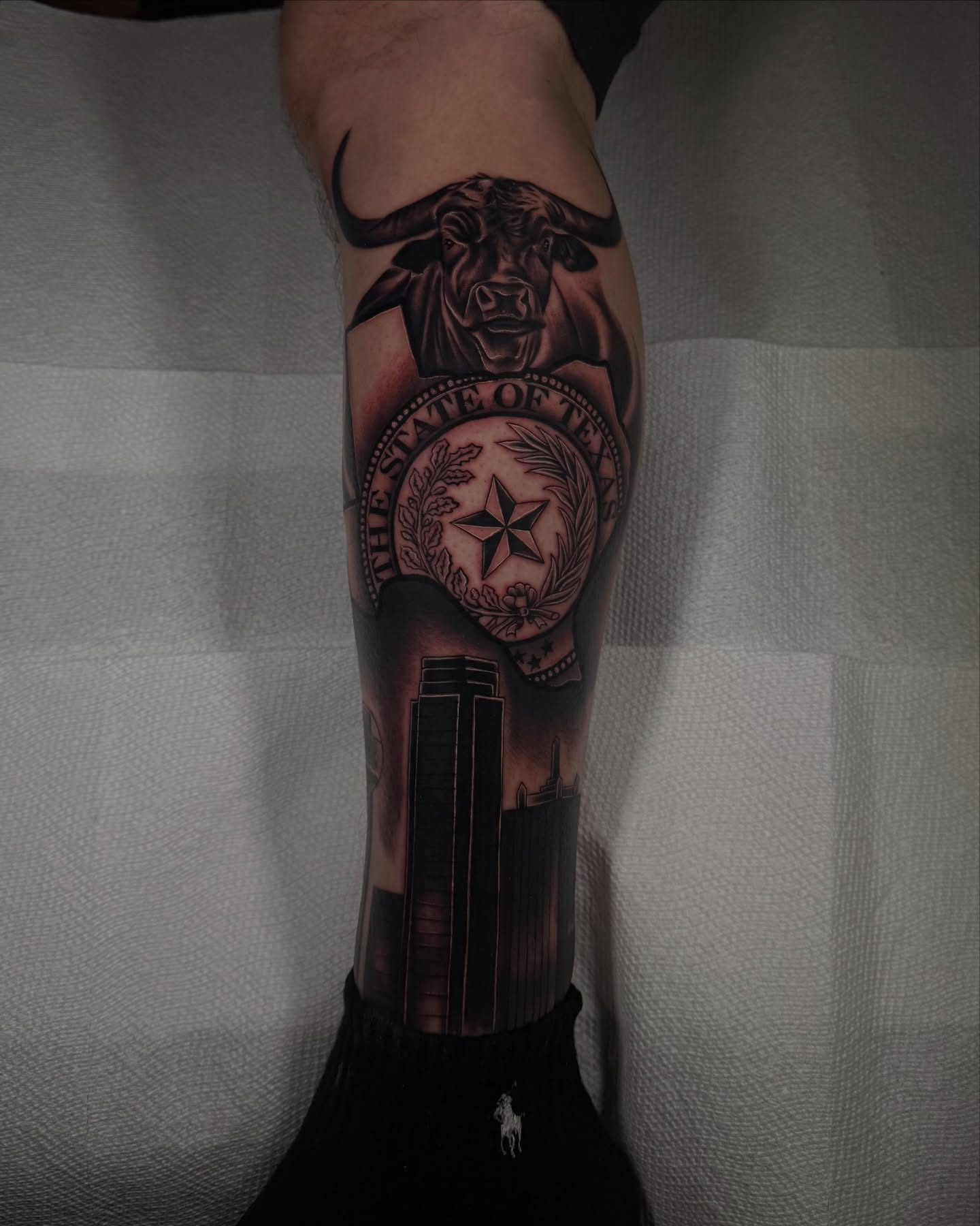 State seal with bull and skyscrapers realism tattoo on the forearm by Aaron Saenz jr