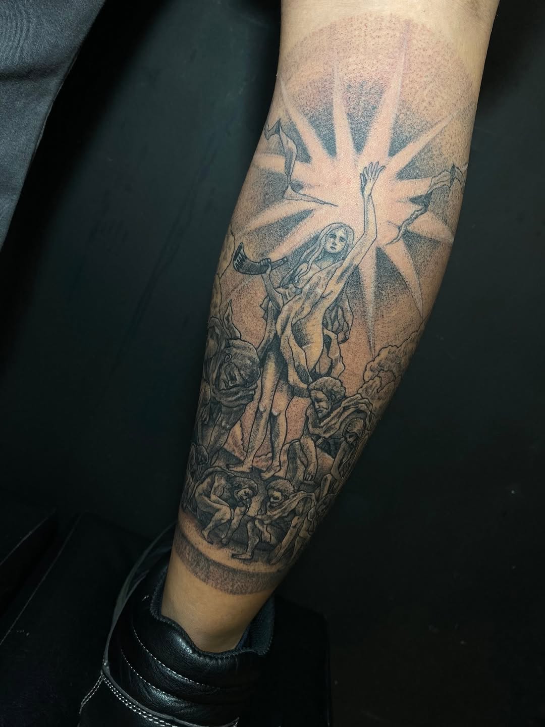Figure with sunburst and surrounding figures realism tattoo on the forearm by Ferds Villanueva