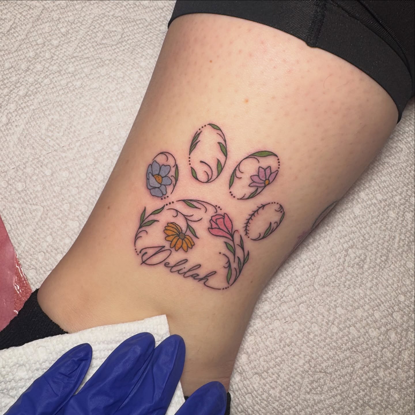 Paw print with floral design ornamental tattoo on the forearm by Lyndze Masters