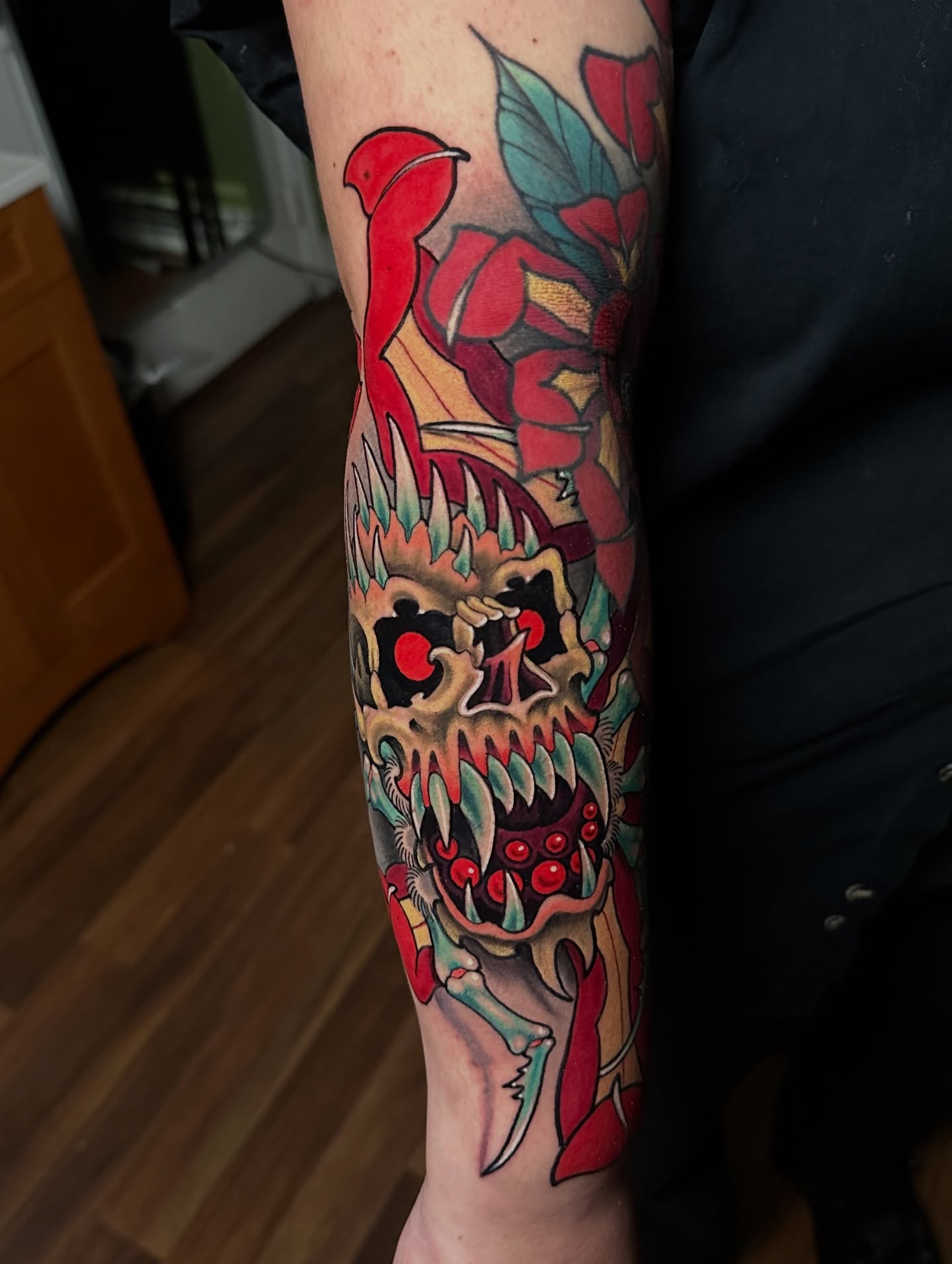 Skull and flowers American traditional tattoo on the forearm by Trevor Burtz