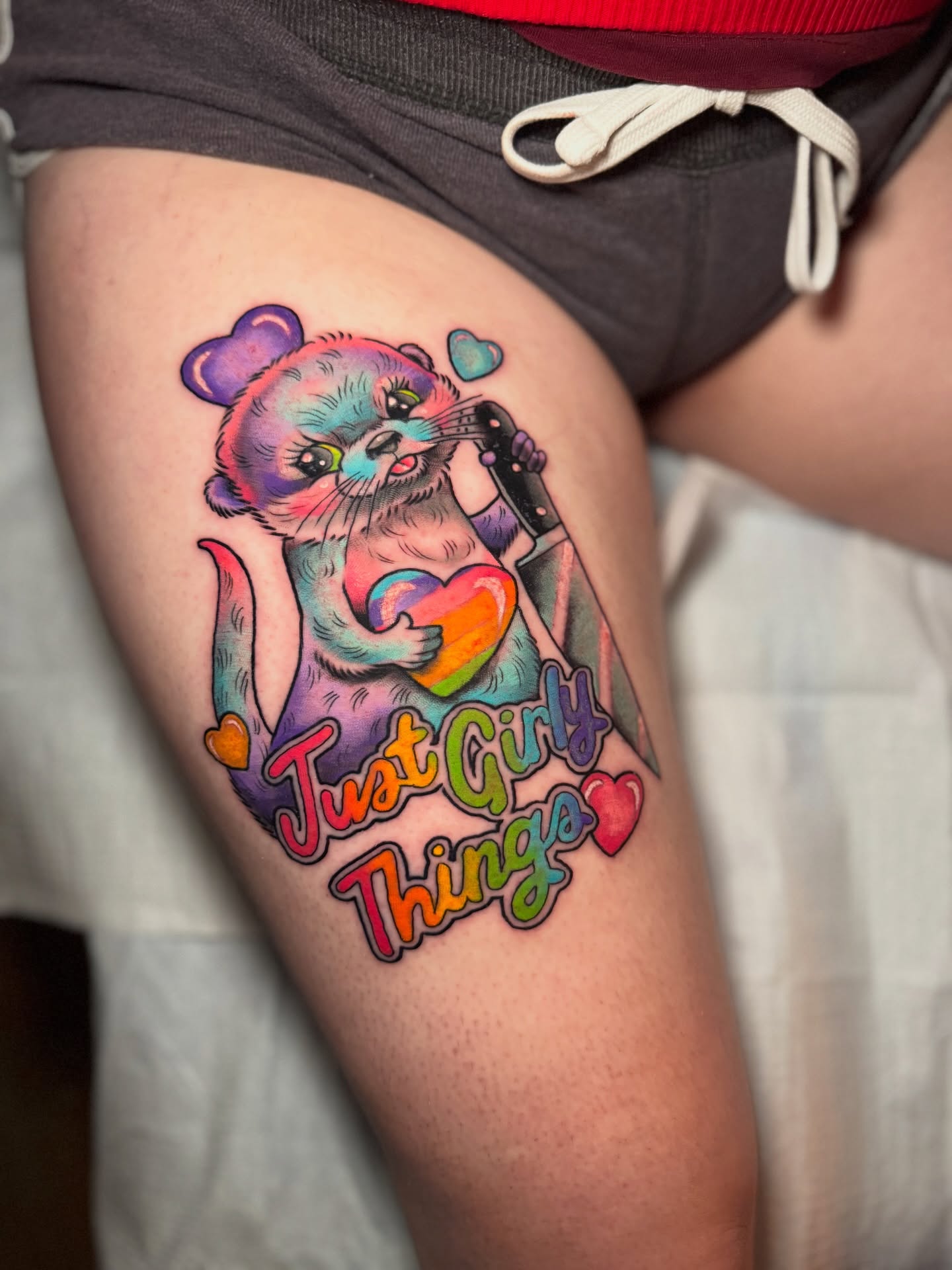 Otter holding heart new school tattoo on the thigh by Stacey Martin Smith