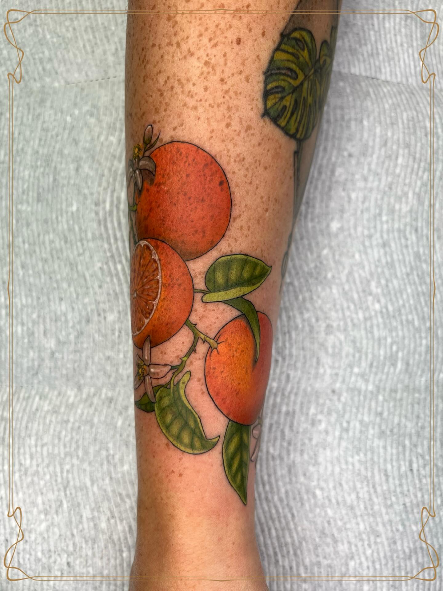 Oranges and leaves realism tattoo on the forearm by Severin Black