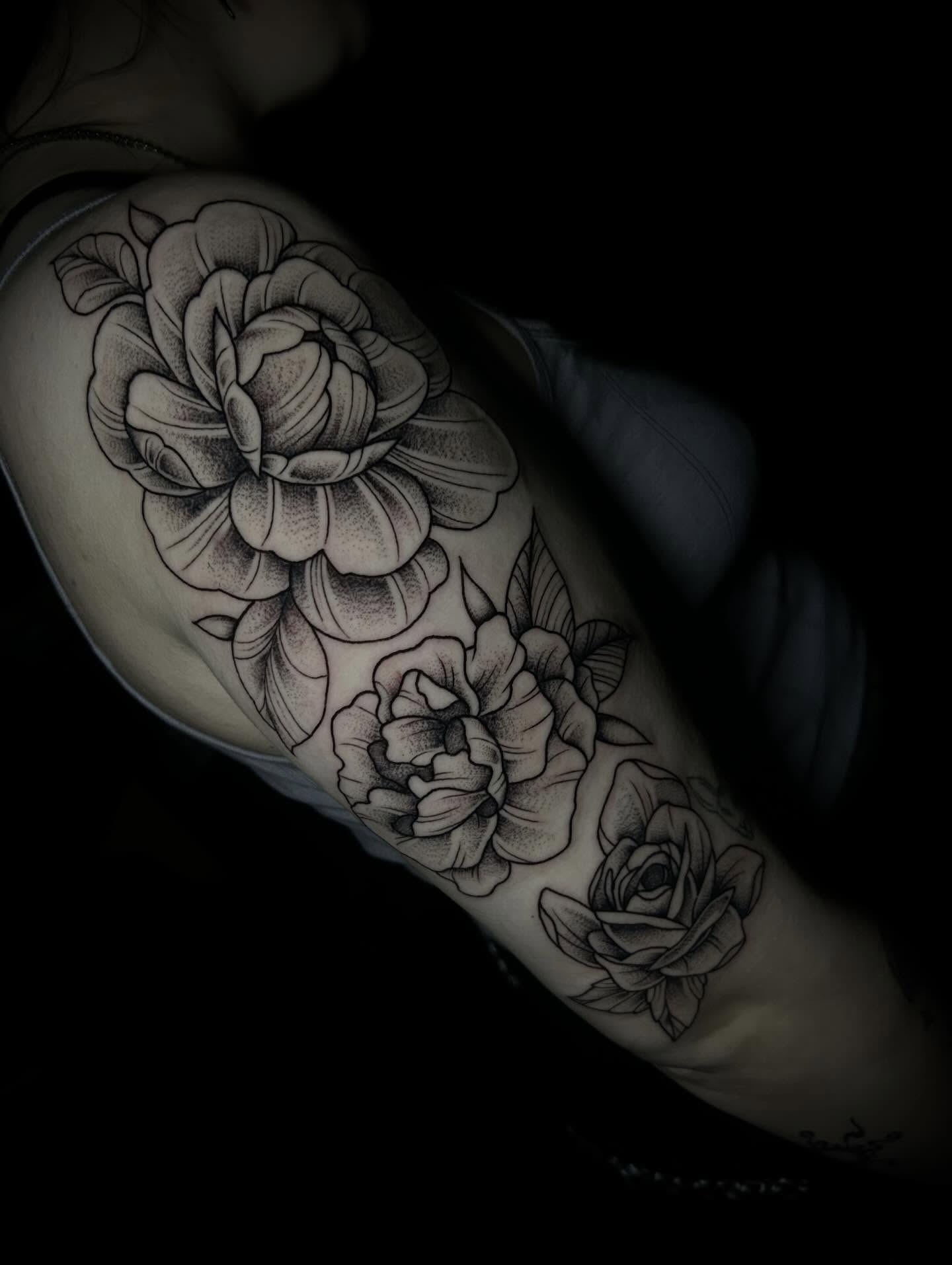 Flowers black and grey tattoo on the upper arm by Heaven Arianna