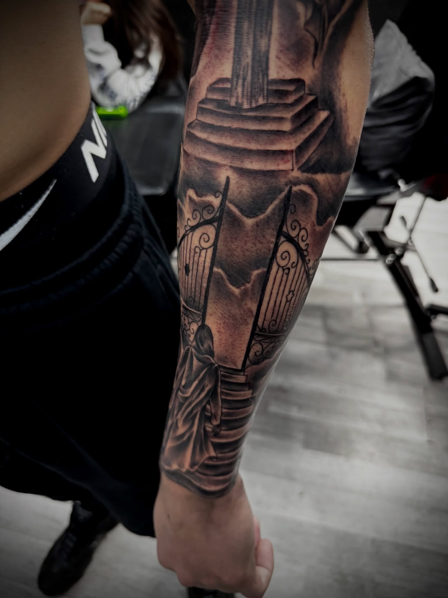 Statue and harp realism tattoo on the forearm by Zeus