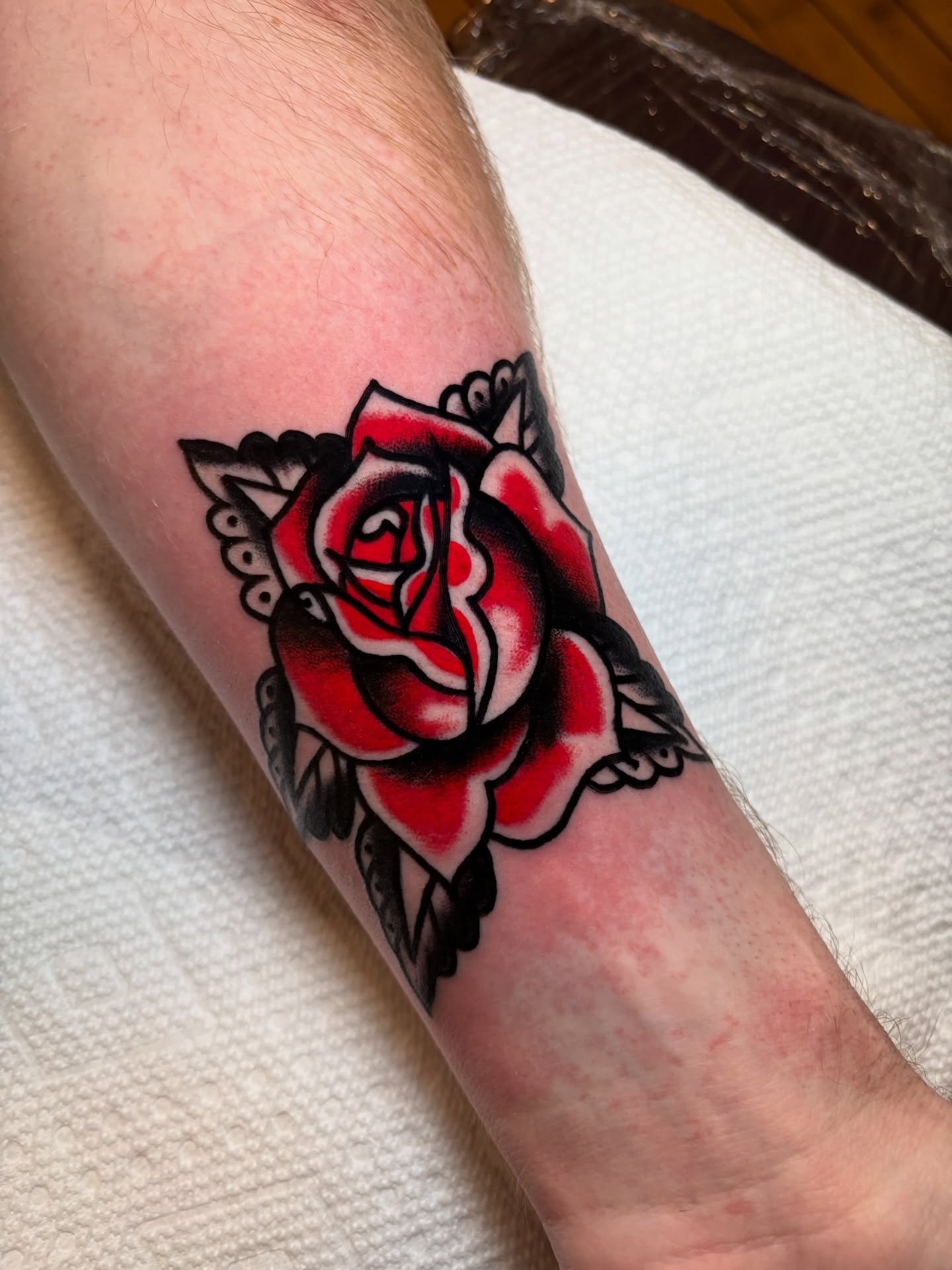 Red rose American traditional tattoo on the forearm by Nick