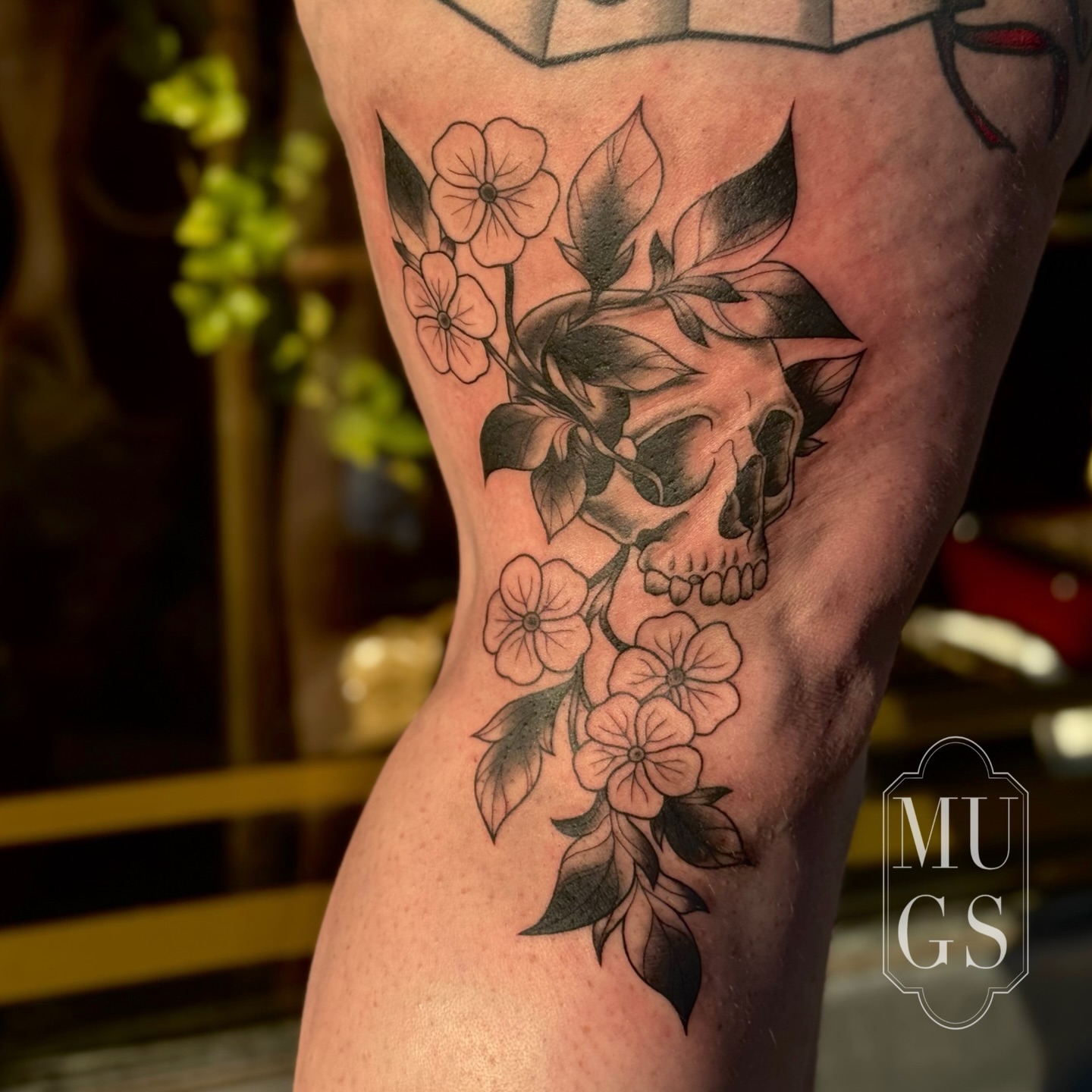 Skull and flowers black and grey tattoo on the forearm by Emily Andreozzi