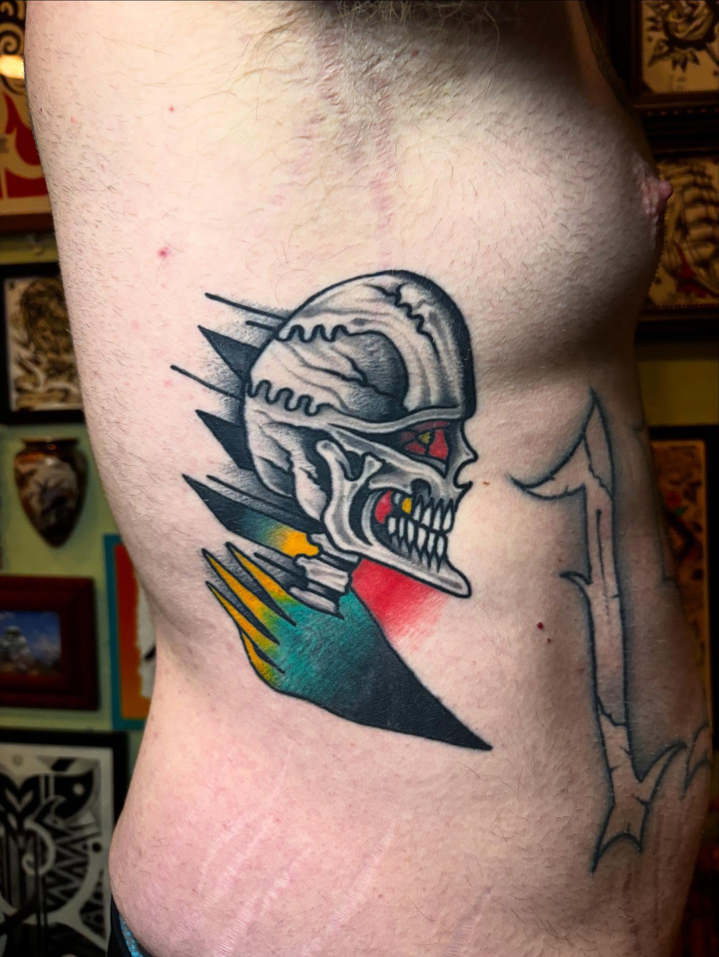 Skull with crossbow American traditional tattoo on the ribs by ๐๐ซ๐ข๐ ๐๐ฅ๐ญ๐จ๐ง๐๐ง