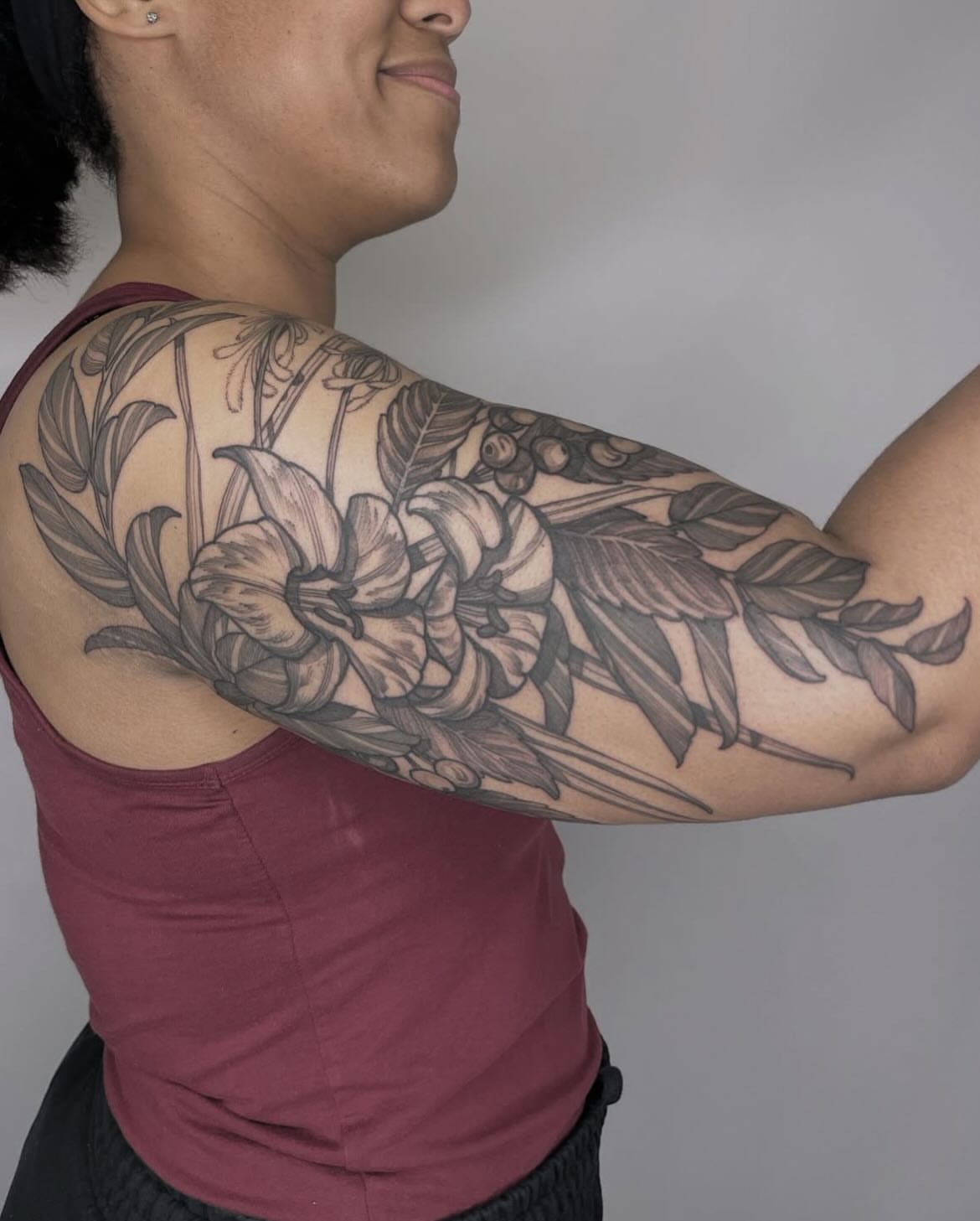 Floral arrangement black and grey tattoo on the upper arm by Carol Jacky