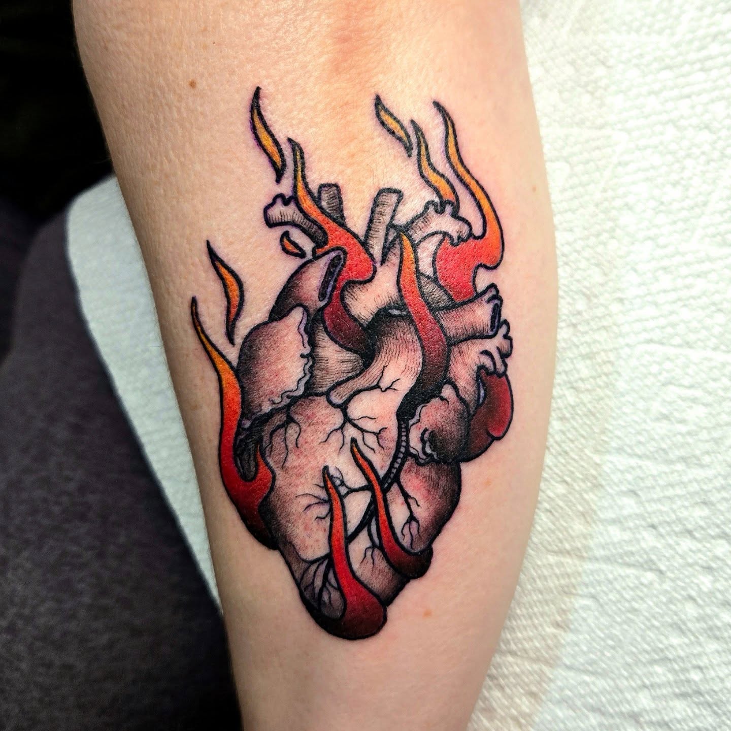 Heart with flames neo-traditional tattoo on the forearm by Amanda Hinrichs