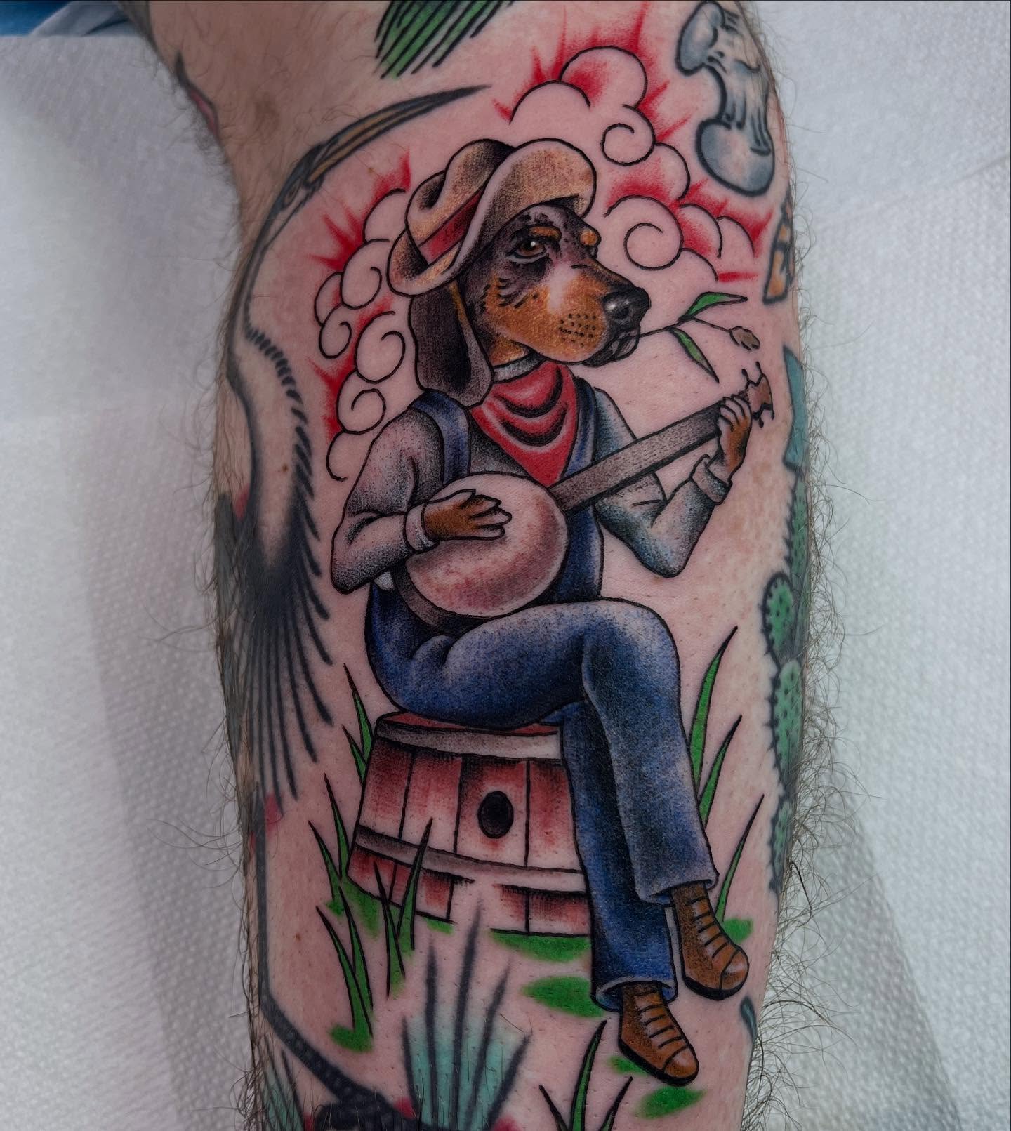 Dachshund playing banjo American traditional tattoo on the forearm by Brian Mcfadden