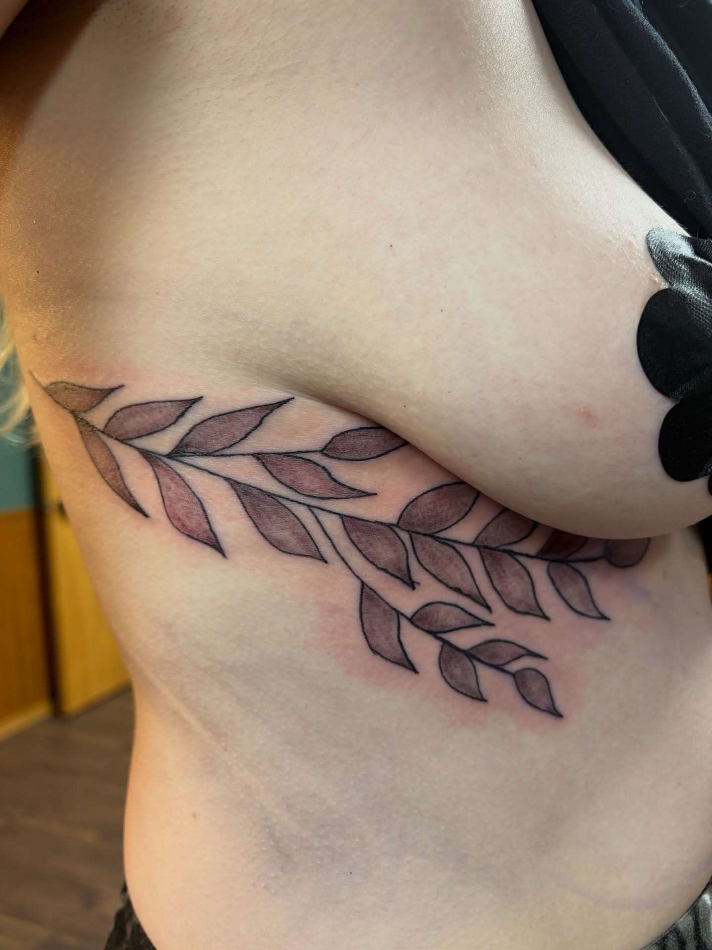 Branch with leaves black and grey tattoo on the ribs by Michelle