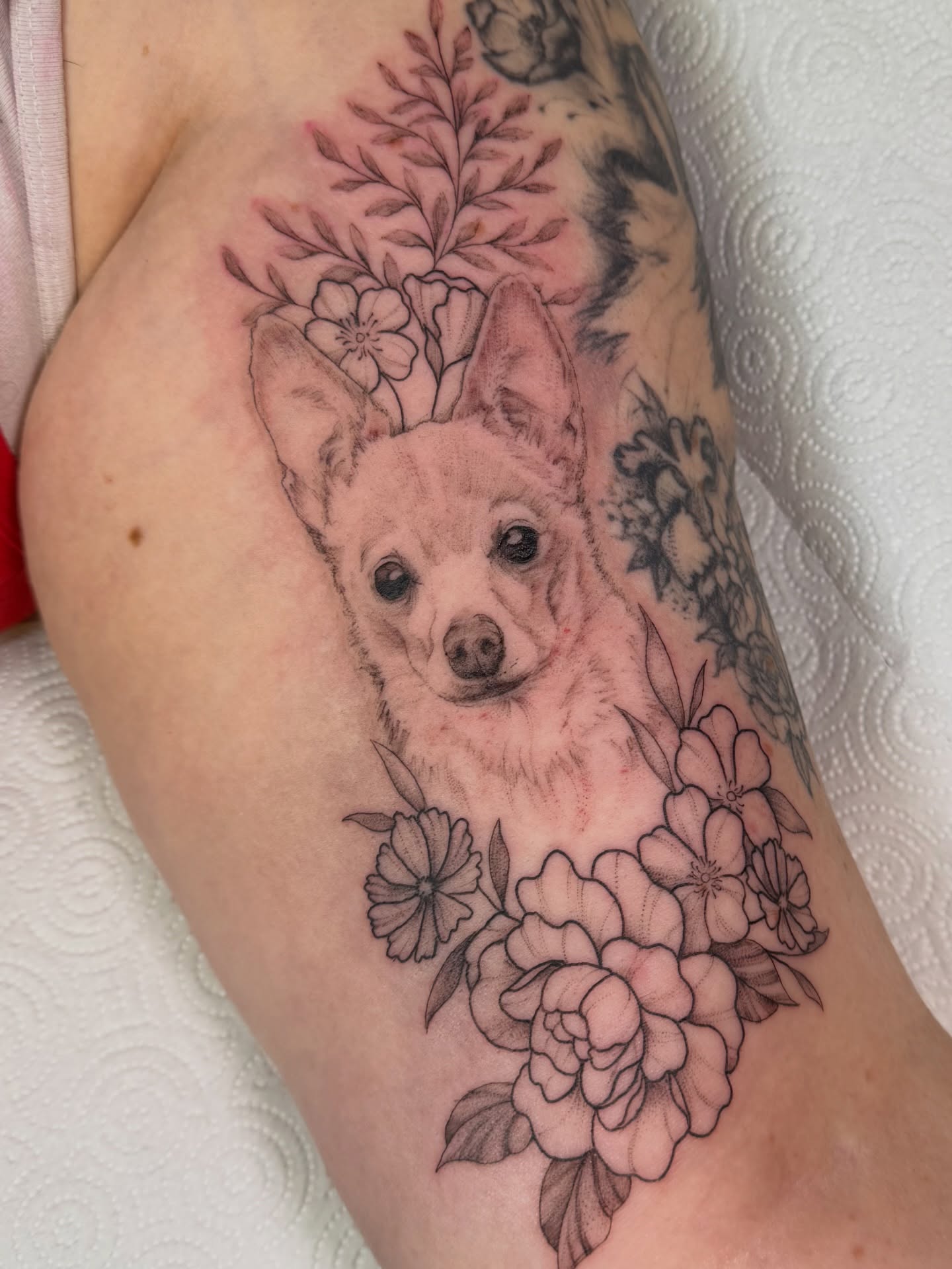 Dog with flowers realism tattoo on the forearm by Dani Fried Tattoos