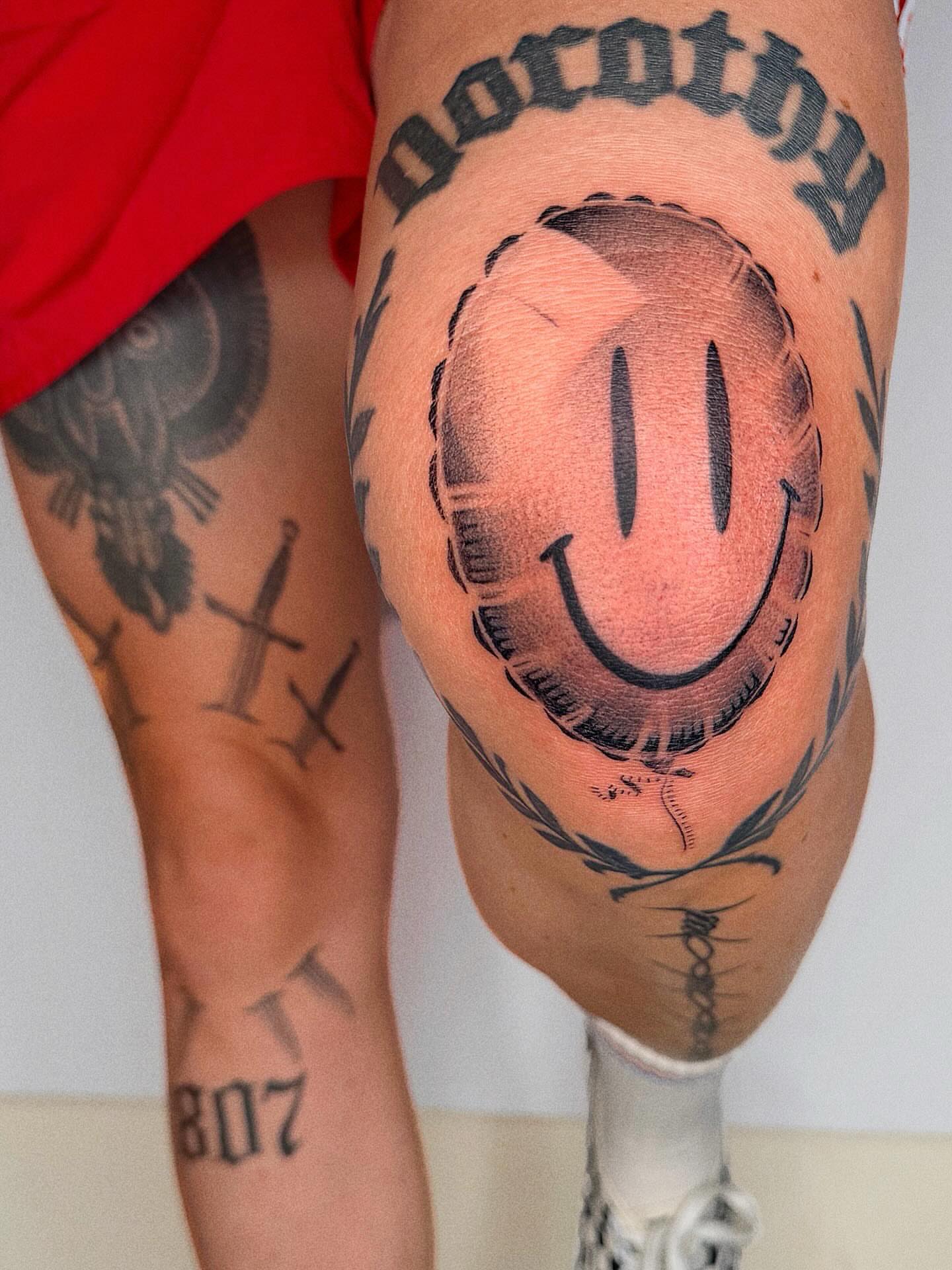 Smiley face black and grey tattoo on the thigh by Jenni Palomaa