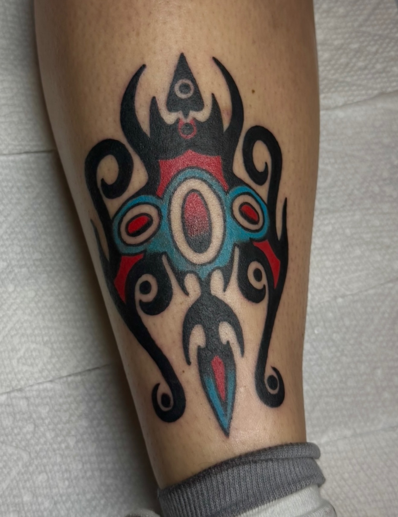 Mask tribal tattoo on the forearm by Zac Clark