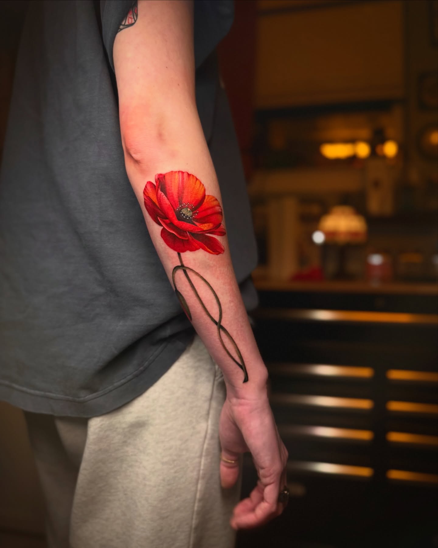 Red poppy realism tattoo on the forearm by laura baldwin