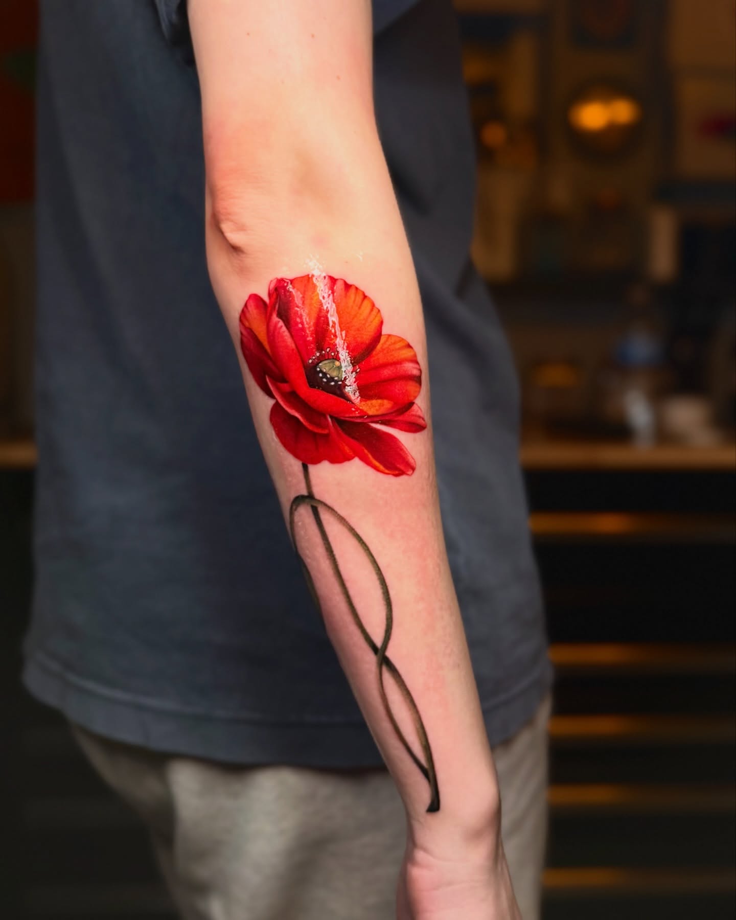 Red poppy realism tattoo on the forearm by laura baldwin