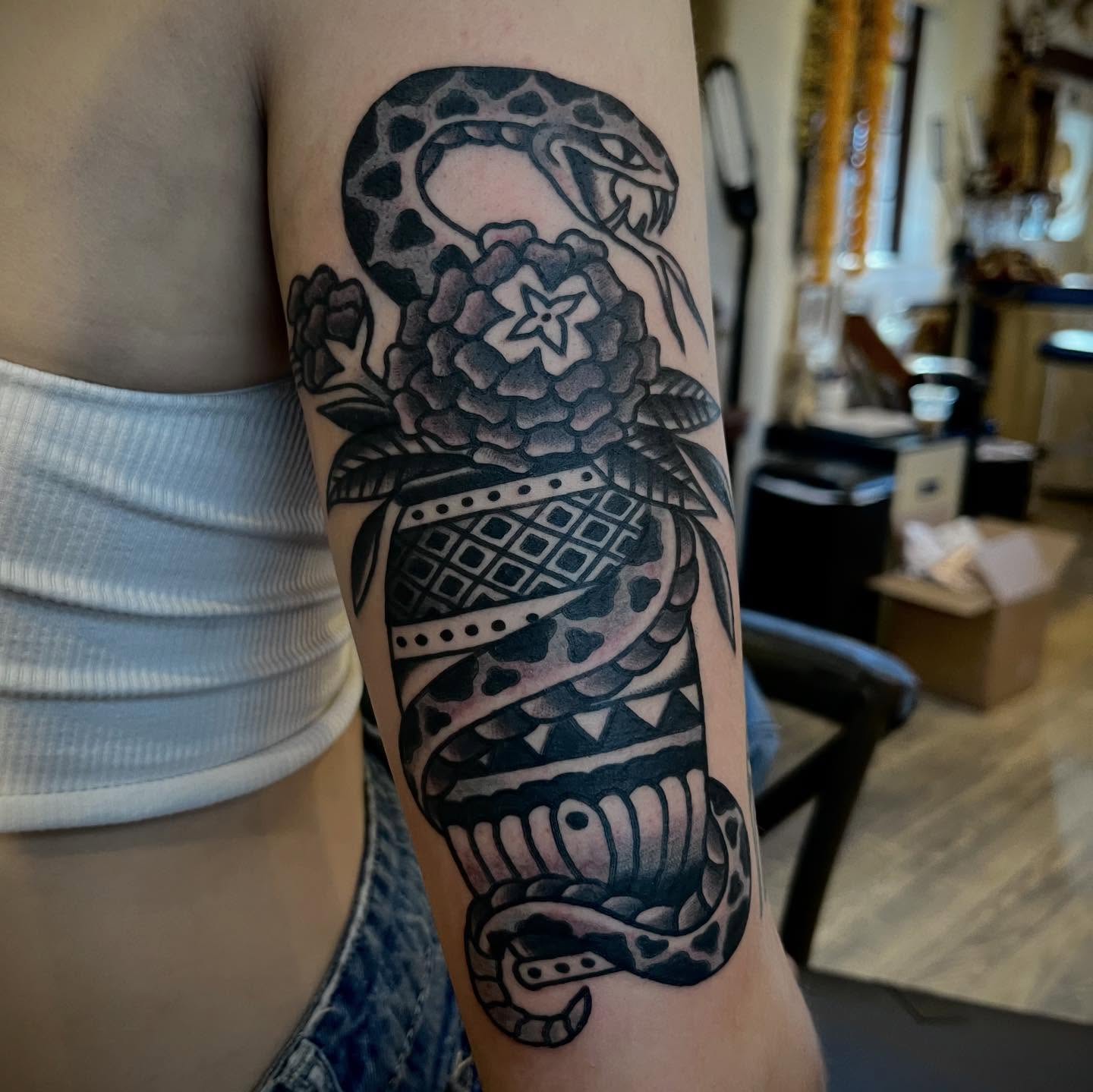 Snake and peony black and grey tattoo on the forearm by Eli Bernal