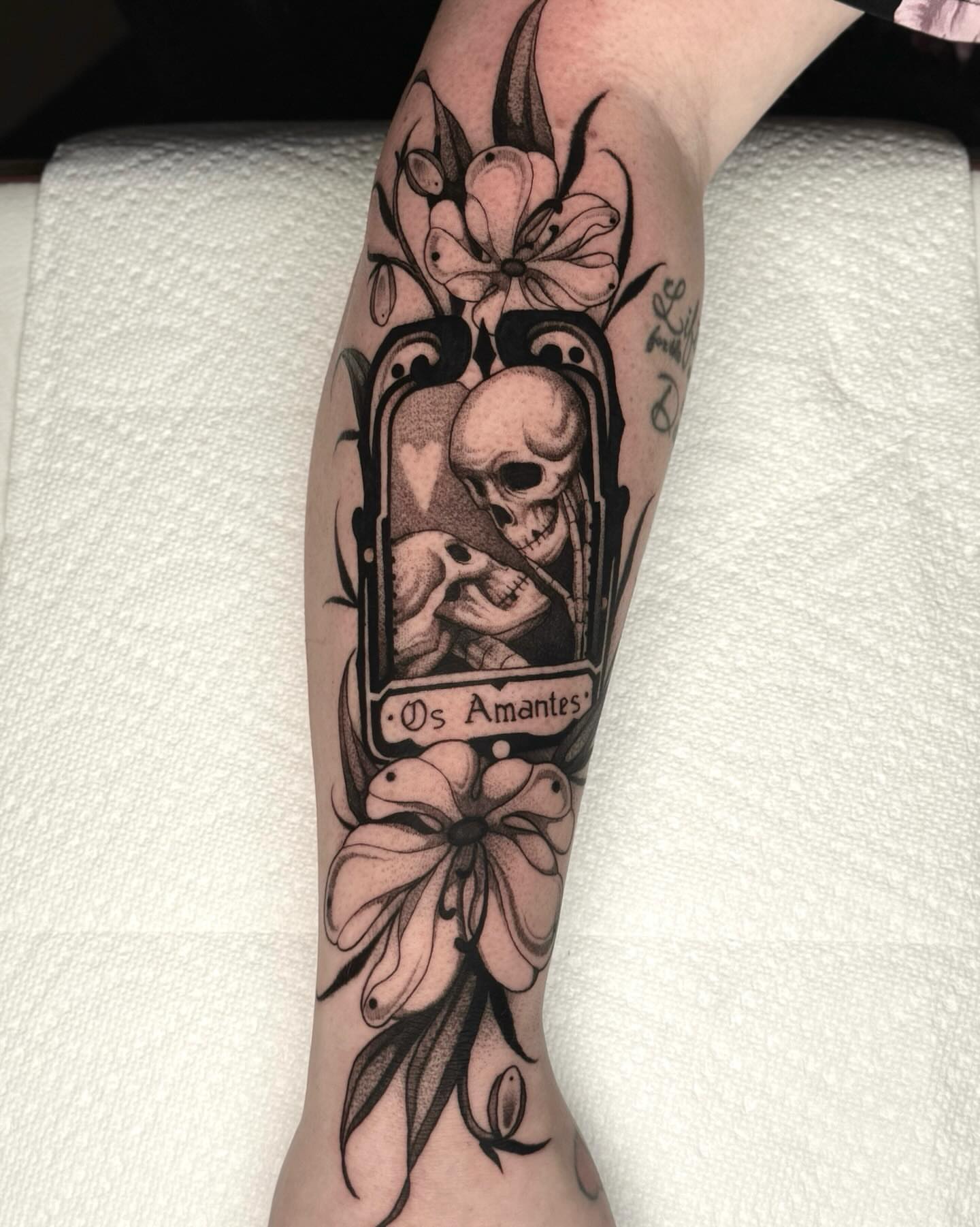 Skull and flowers black and grey tattoo on the forearm by jada