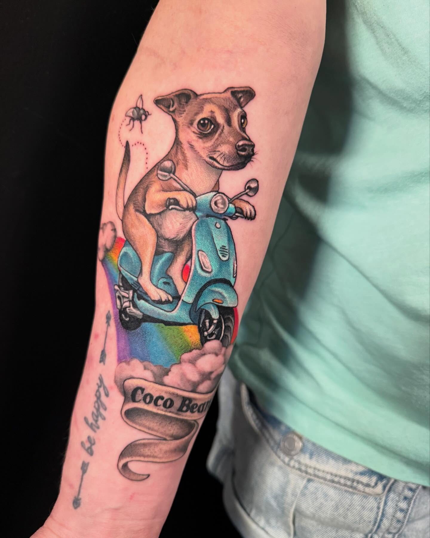 Dog riding scooter realism tattoo on the forearm by Jade Lewis