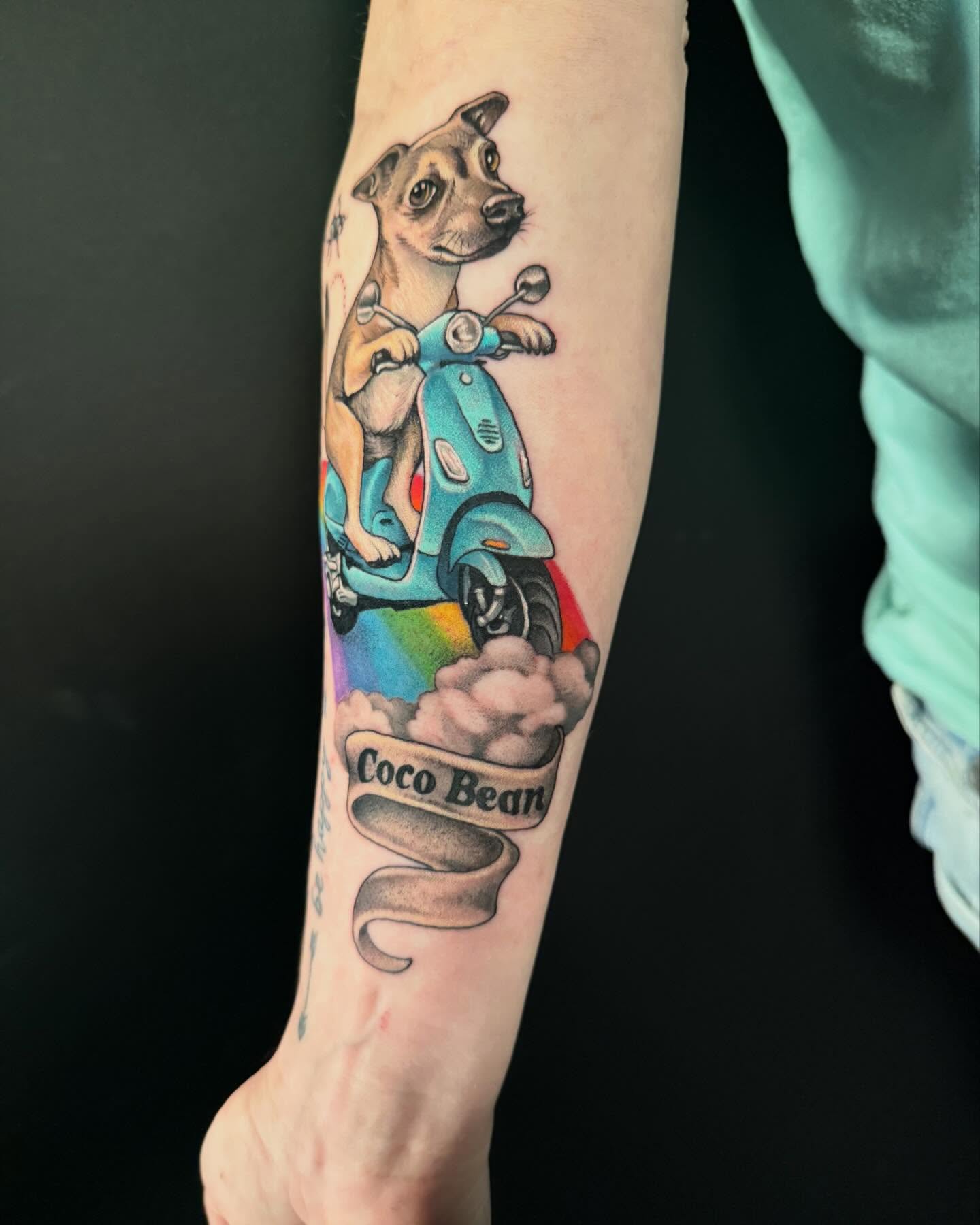 Dog riding scooter realism tattoo on the forearm by Jade Lewis