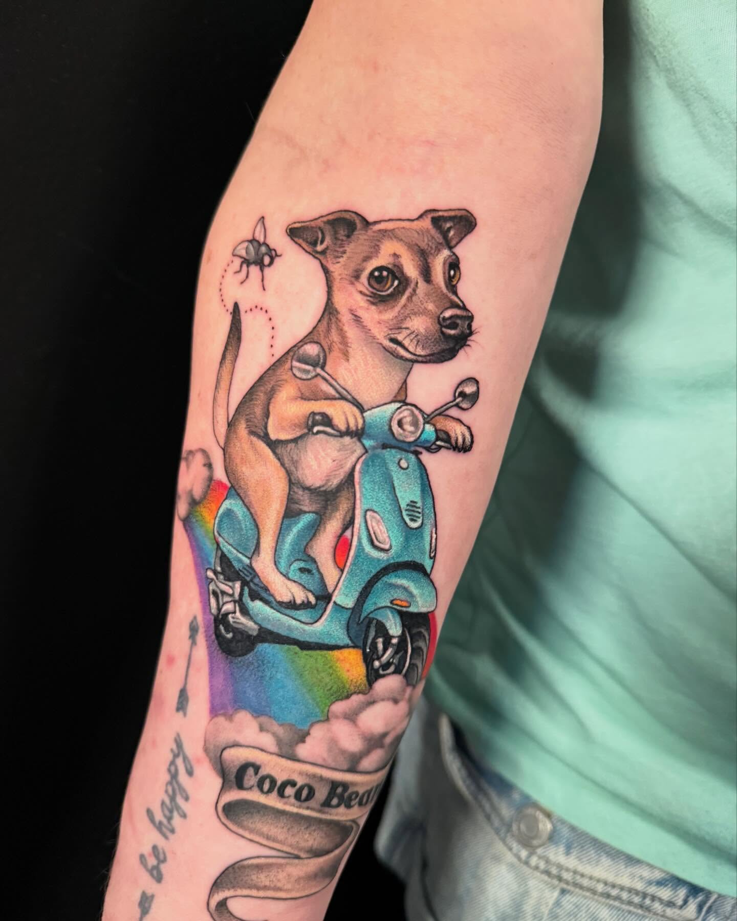 Dog riding scooter realism tattoo on the forearm by Jade Lewis
