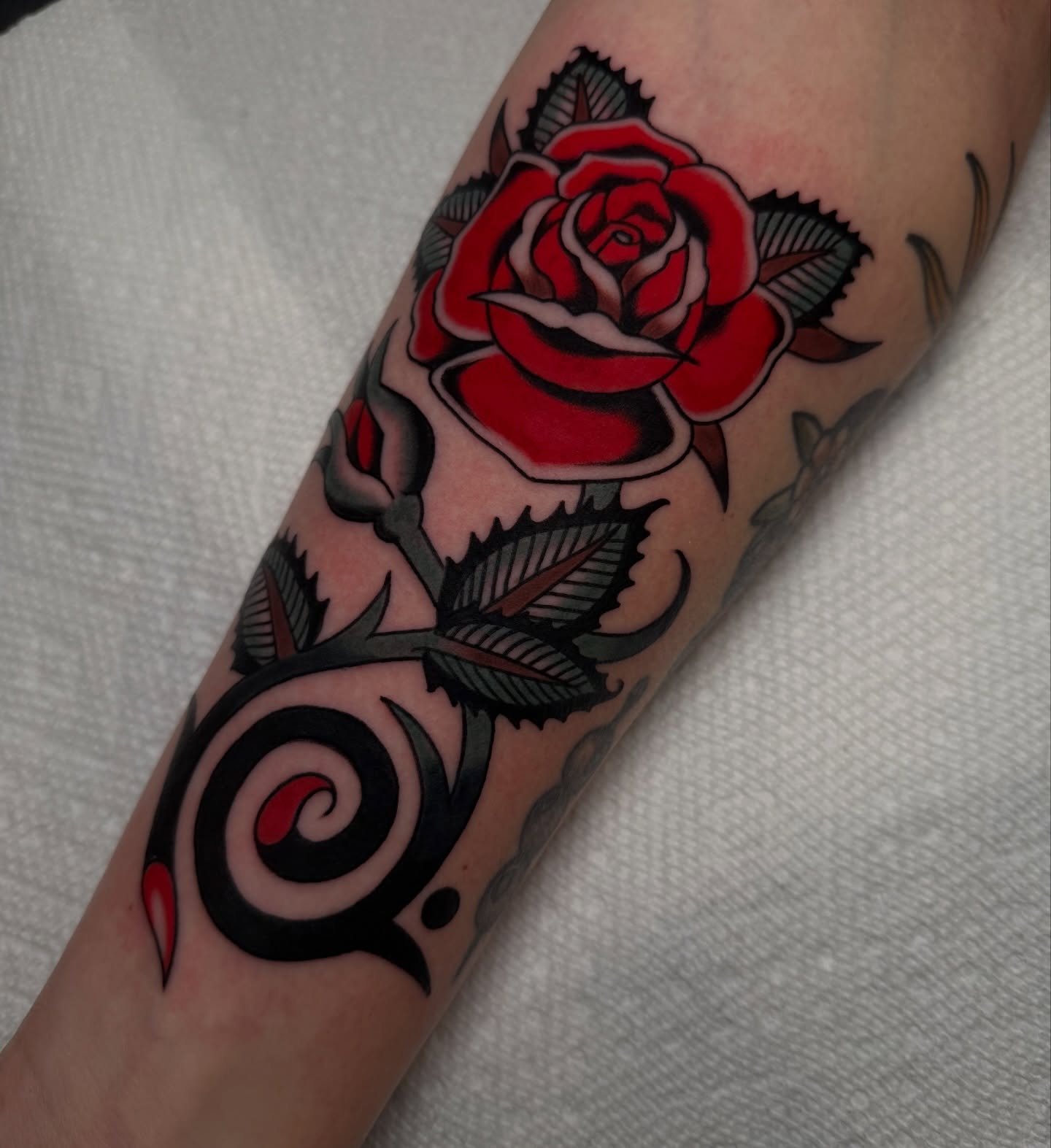 Red rose American traditional tattoo on the forearm by kate