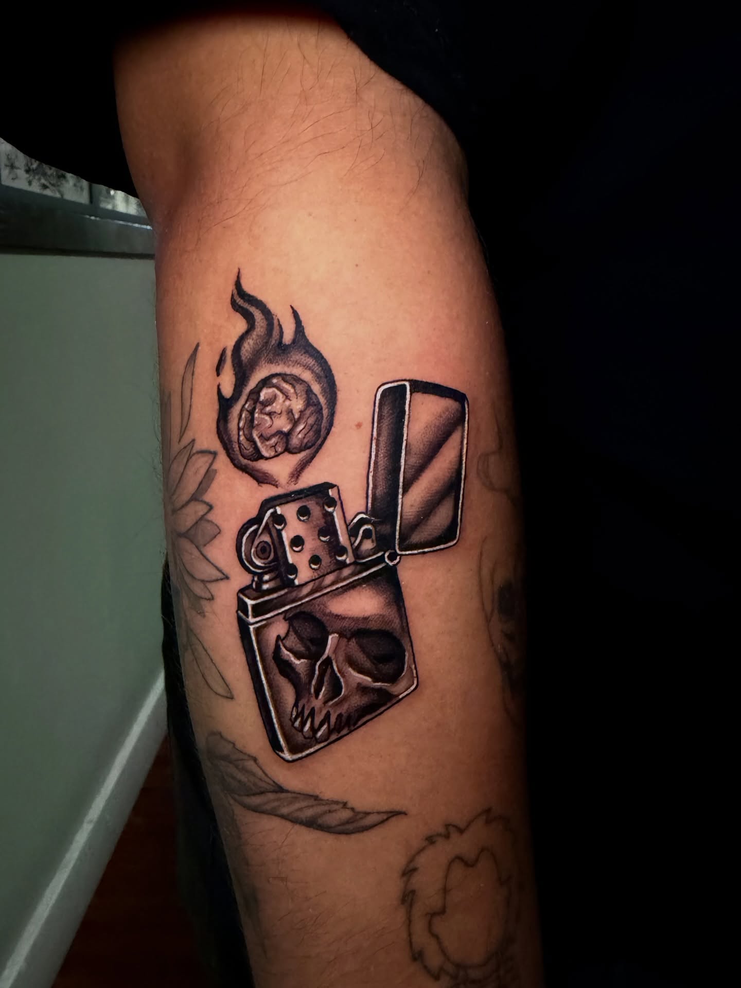 Lighter and skull black and grey tattoo on the forearm by Marisa Biddle