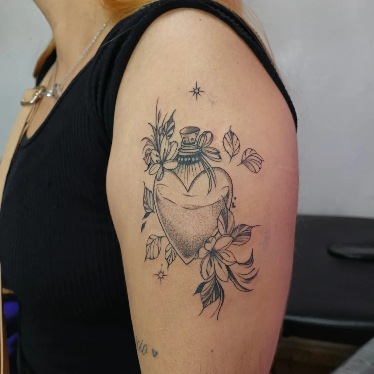 Heart-shaped bottle with flowers dotwork tattoo on the shoulder by Alexander Tattooink