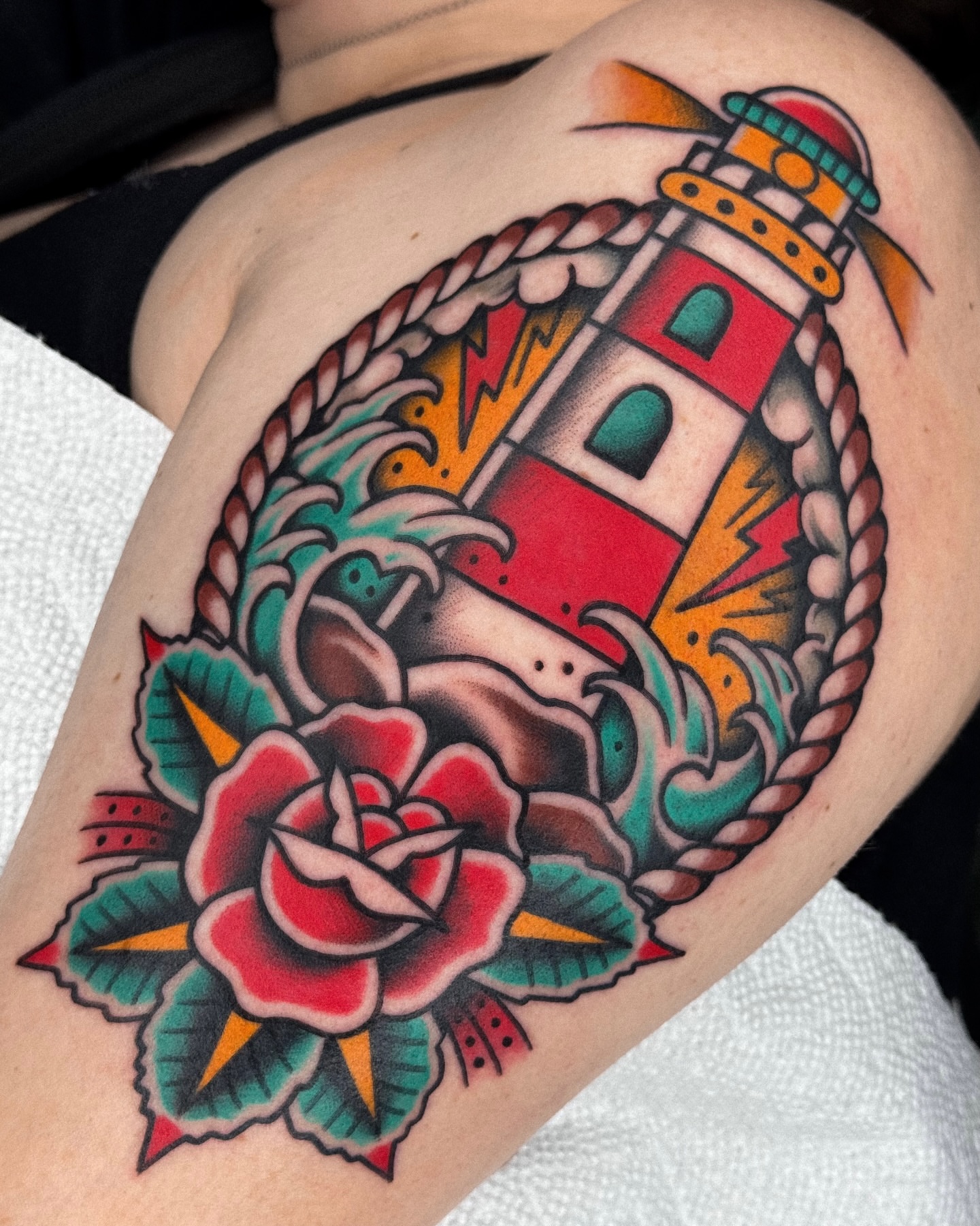Lighthouse and rose American traditional tattoo on the shoulder by Samuel Dickey
