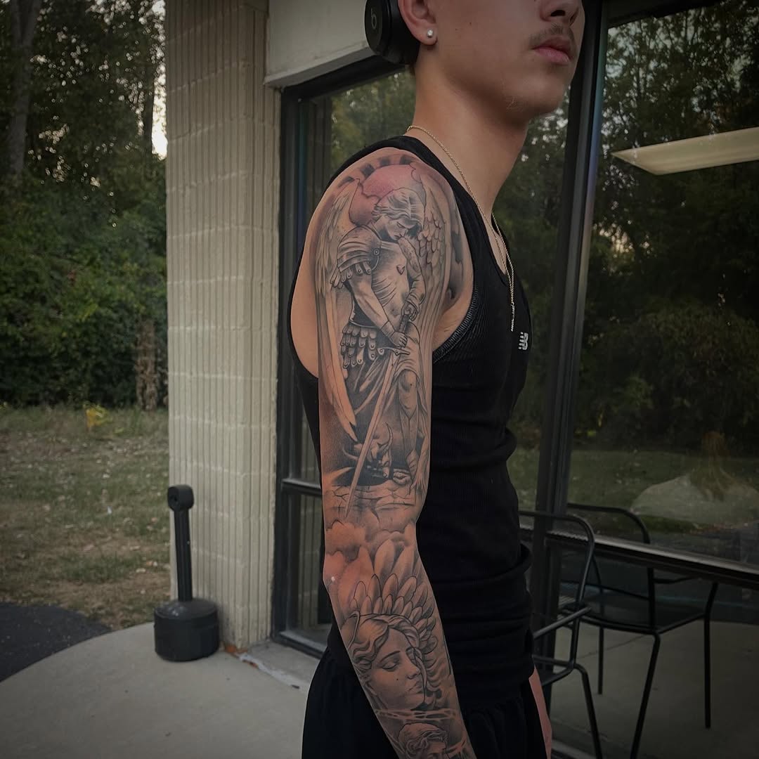 Angel and woman realism tattoo on the upper arm by Chris Torres
