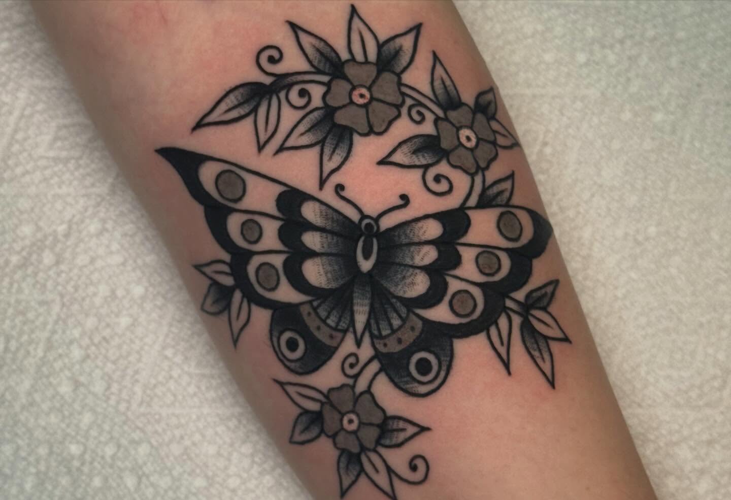 Butterfly and flowers American traditional tattoo on the forearm by Painted Peach Tattooer