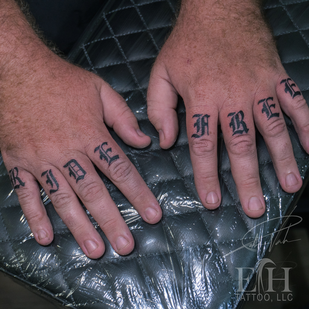 RIDE lettering on fingers tattoo on the hand by Donald Voelker