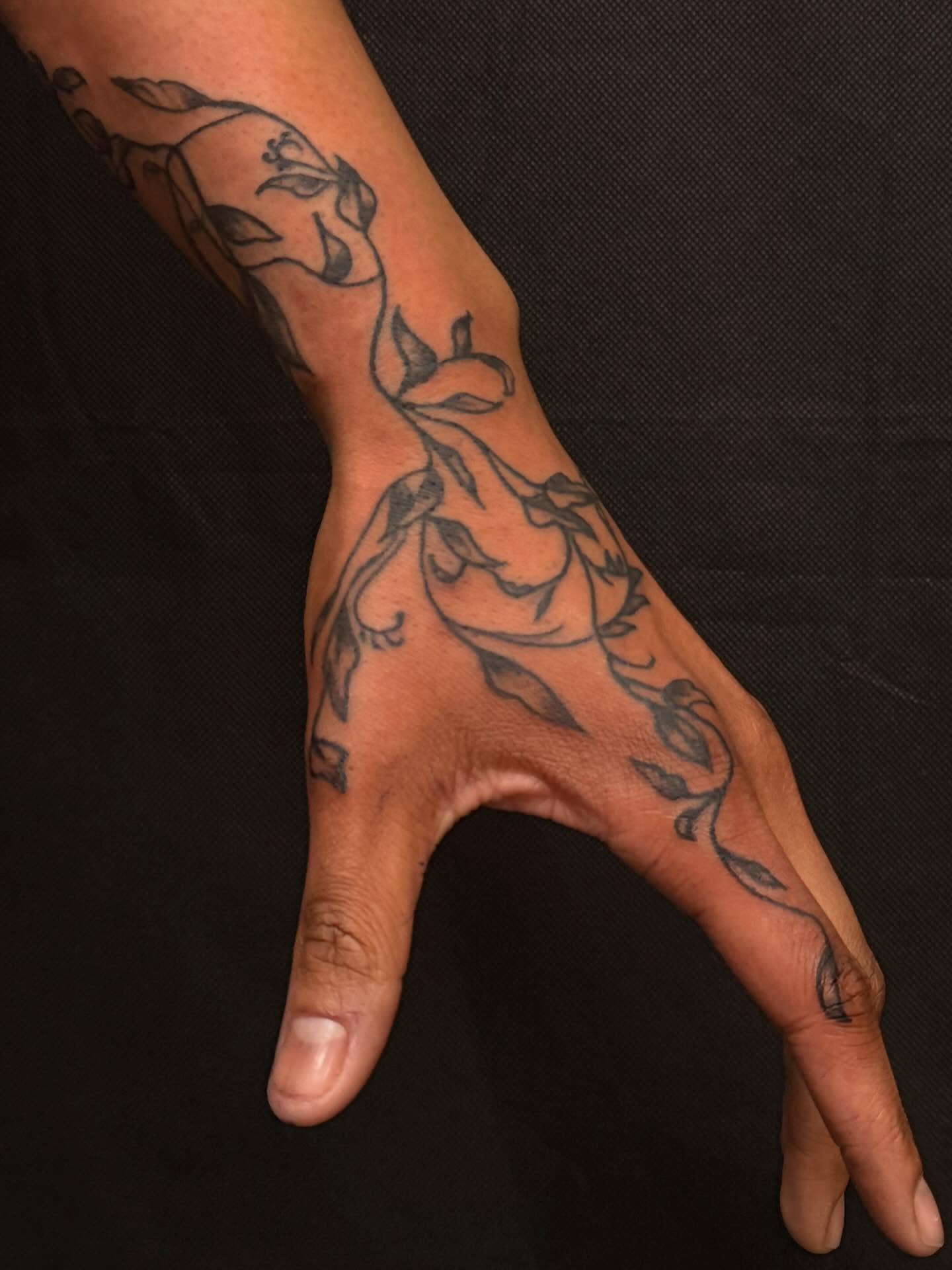 Floral vine black and grey tattoo on the hand by cortez