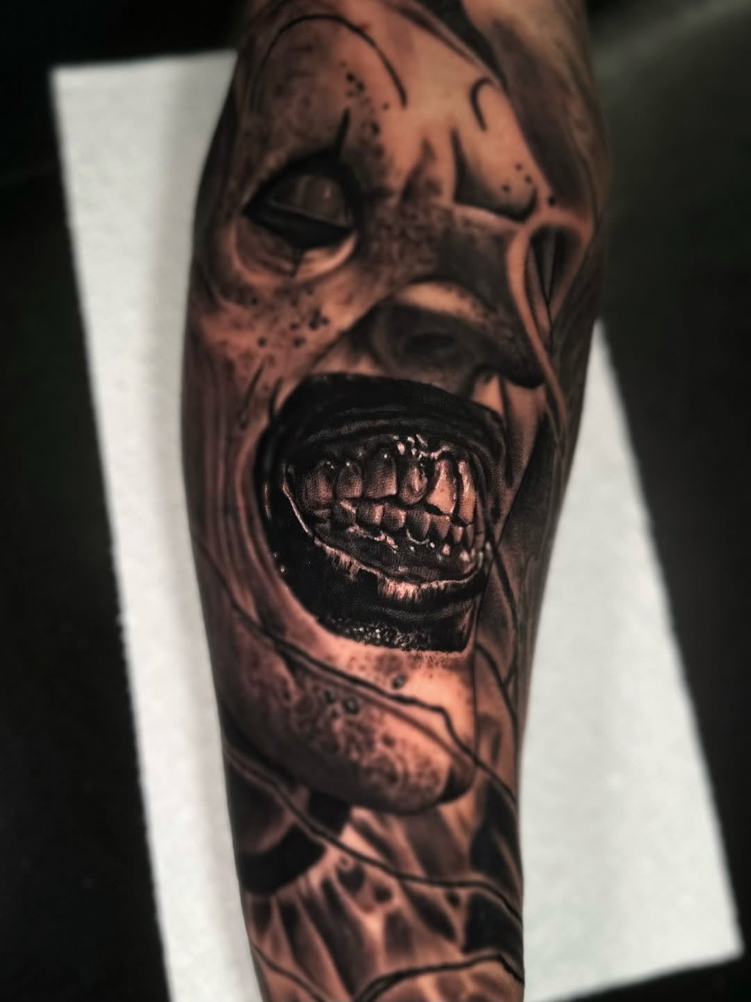 Creepy clown face realism tattoo on the forearm by Jesse White, Mentor, Ohio