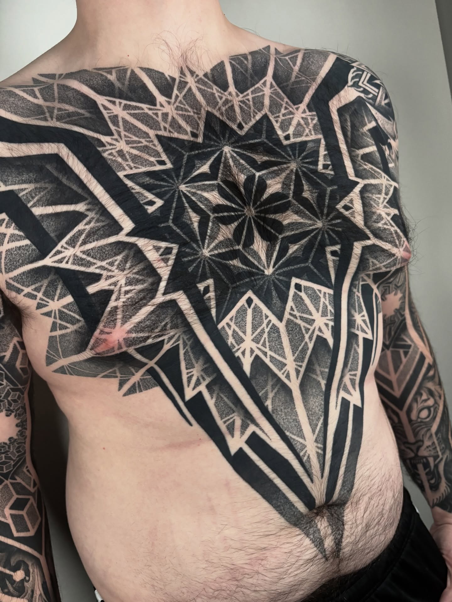 Geometric pattern dotwork tattoo on the chest by Mitch Koch