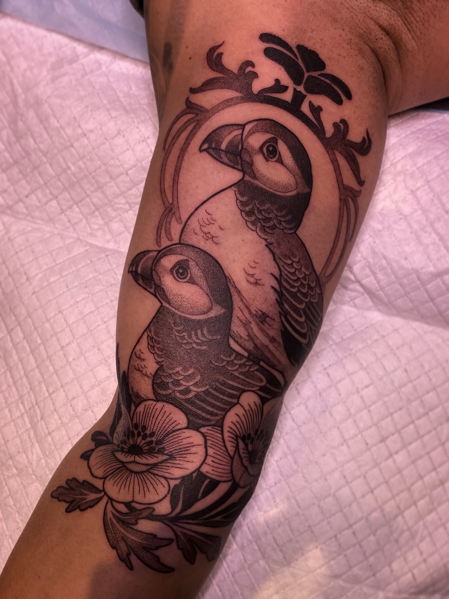 Puffins and flowers black and grey tattoo on the forearm by Natasha Dickinson