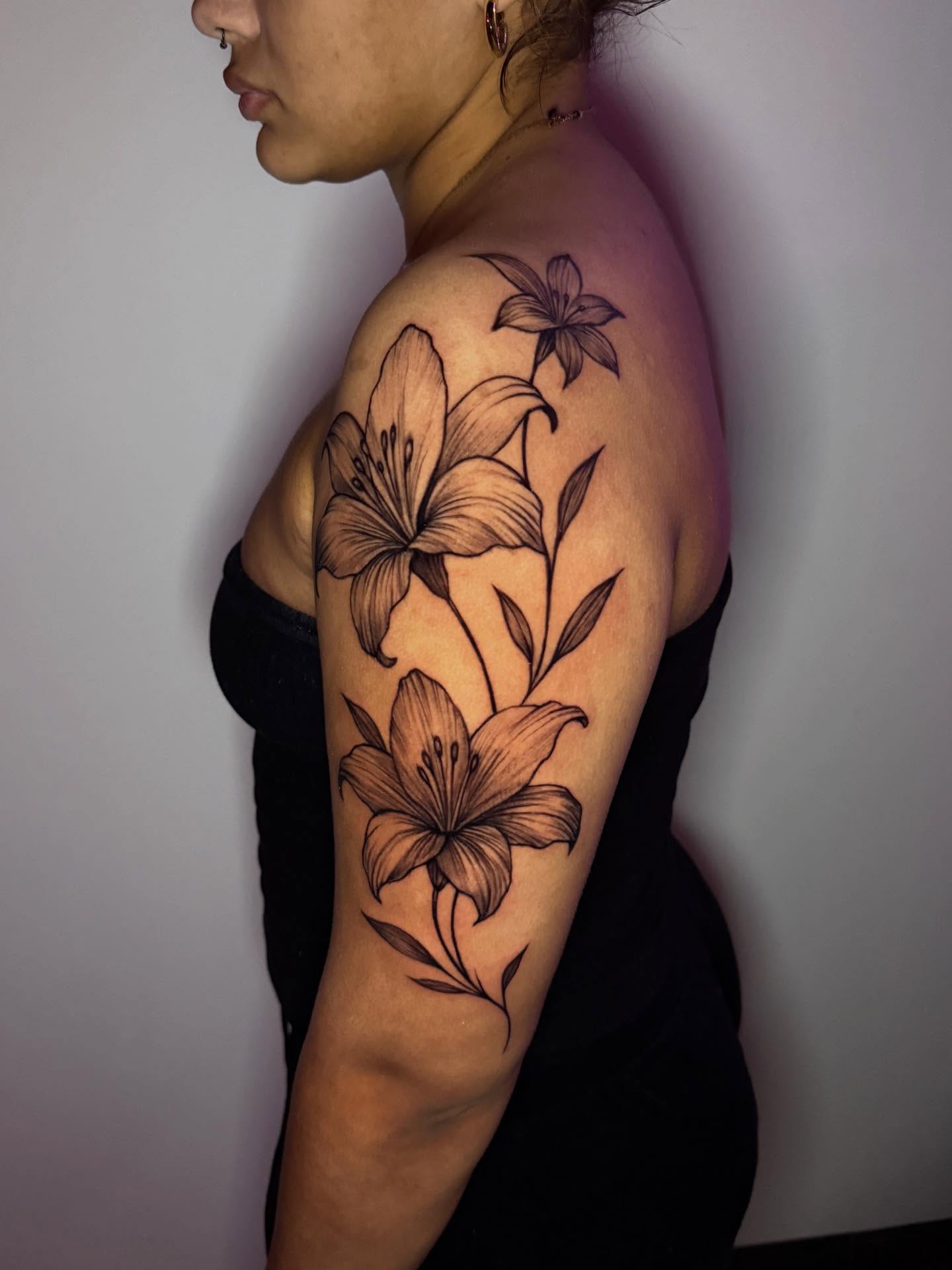 Lilies black and grey tattoo on the upper arm by 📍 Austin
