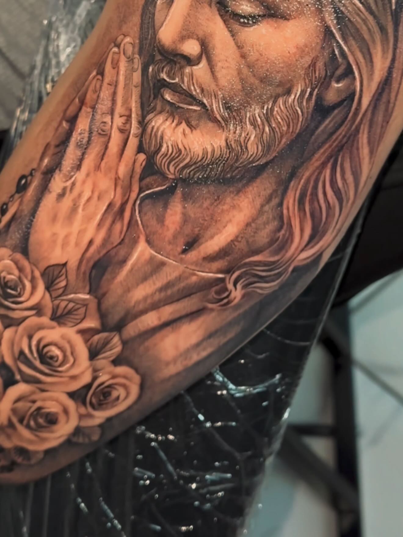 Praying jesus with roses realism tattoo on the upper arm by Adrian gonzalez...