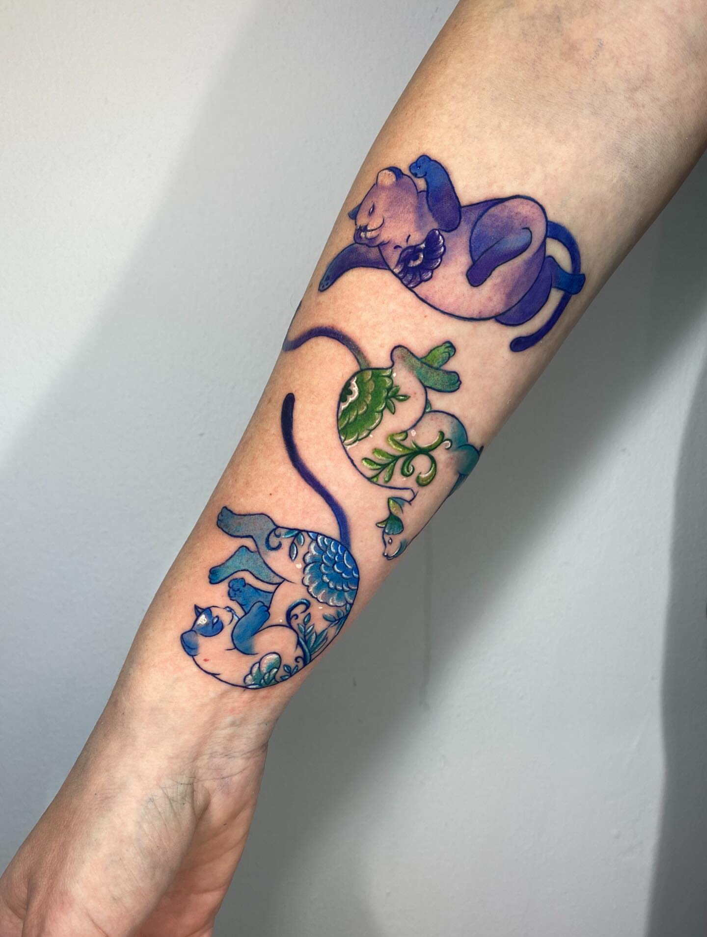 Cat and fish new school tattoo on the forearm by Tattoo Medellin