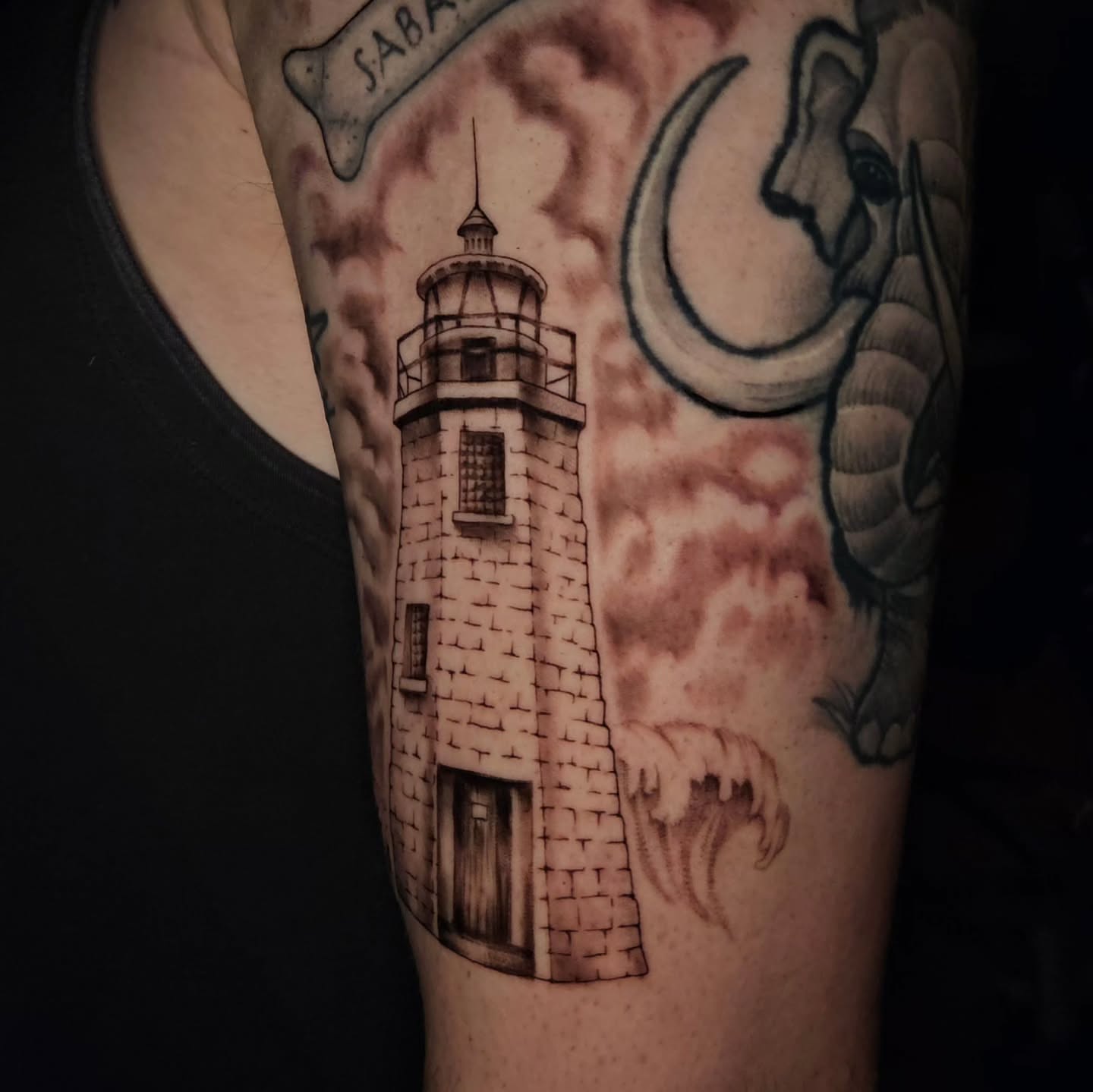 Lighthouse and elephant realism tattoo on the forearm by Courtlyn Bliss