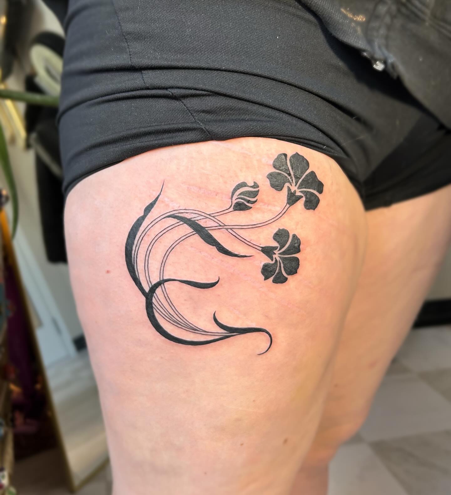 Clover and vine black and grey tattoo on the thigh by kuna ink