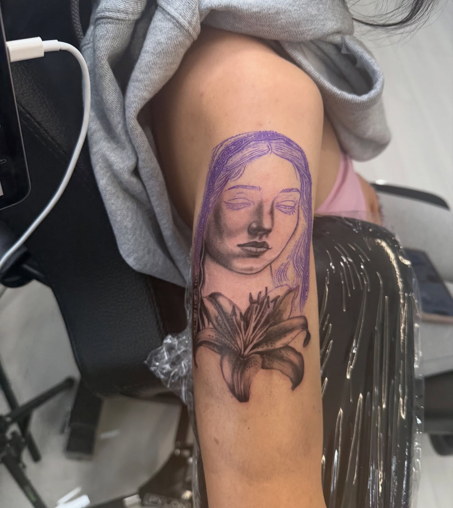Woman's face with lily realism tattoo on the forearm by ♍️𝒾𝒸𝒽𝑒𝓁𝓁𝑒⁺‧₊˚ ཐི⋆♱⋆ཋྀ ˚₊‧⁺, Charlotte, North Carolina