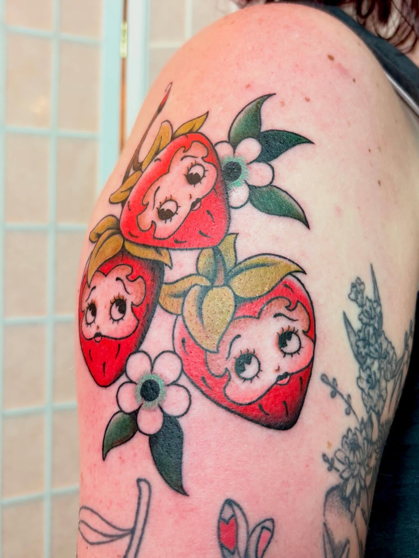 Strawberry faces American traditional tattoo on the shoulder by Leah Leinani